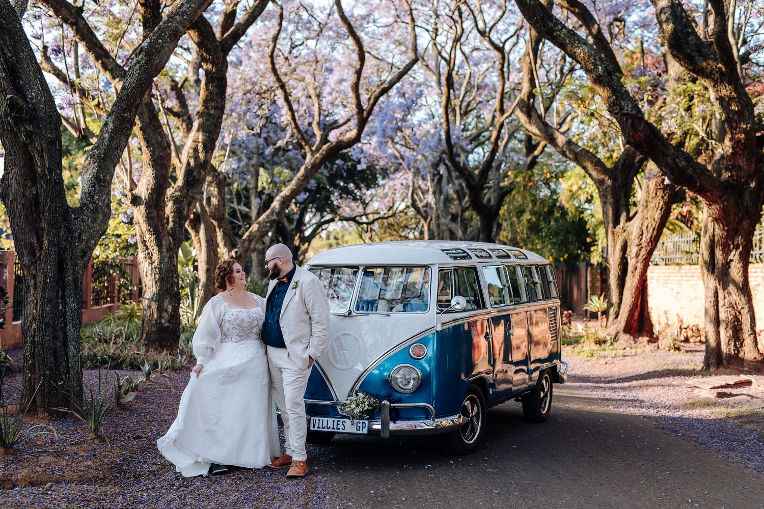 Vintage Volkswagen van parked under autumn trees during a rustic outdoor wedding ceremony.