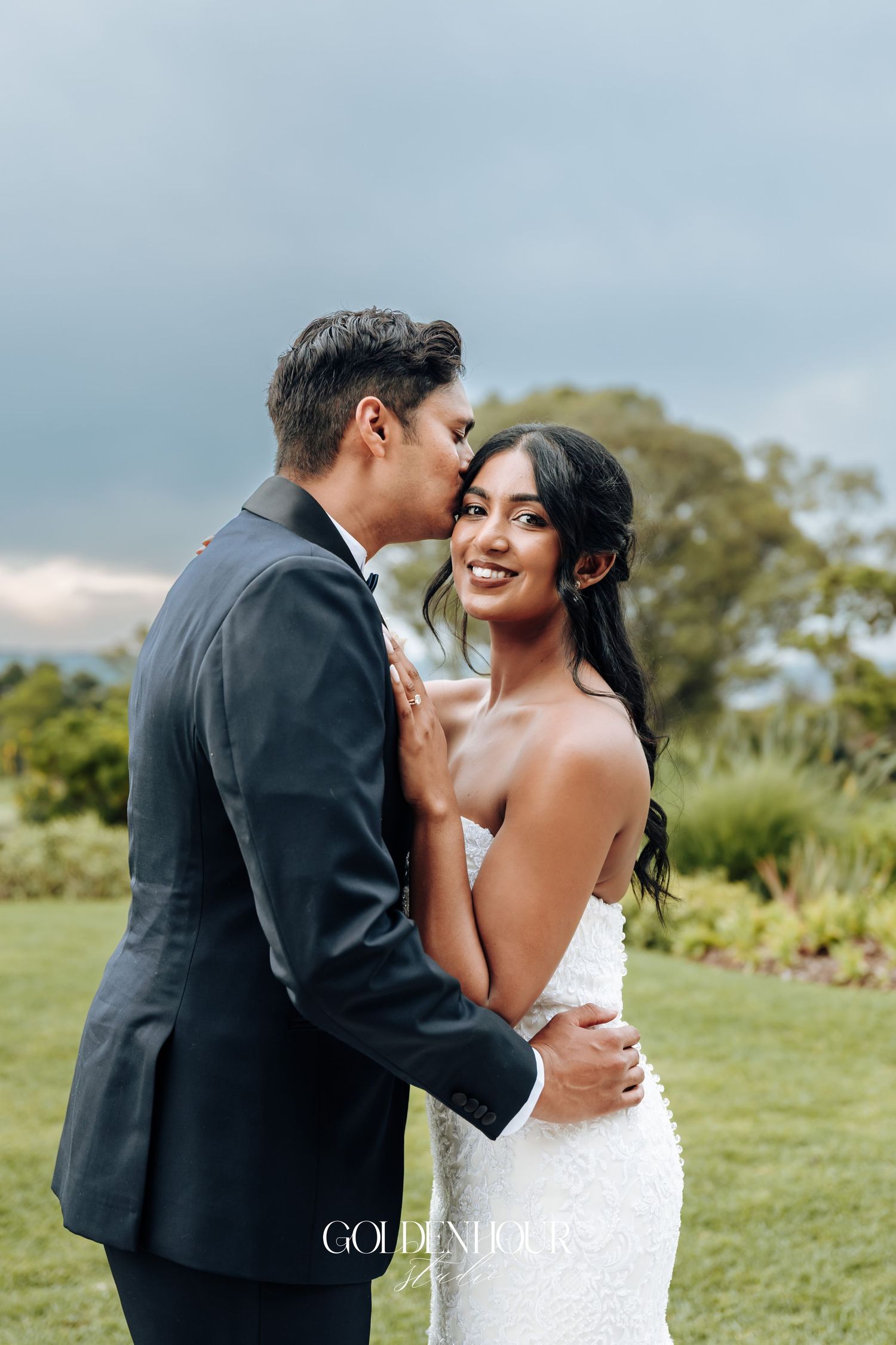 Newlyweds sharing intimate moment in outdoor garden setting.