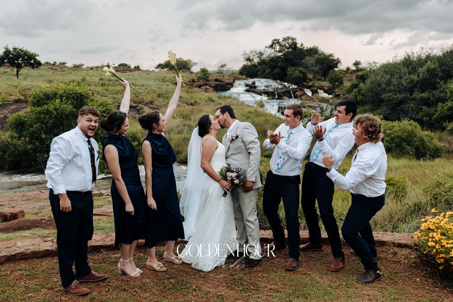 Wedding party poses together outdoors in mix of formal attire.