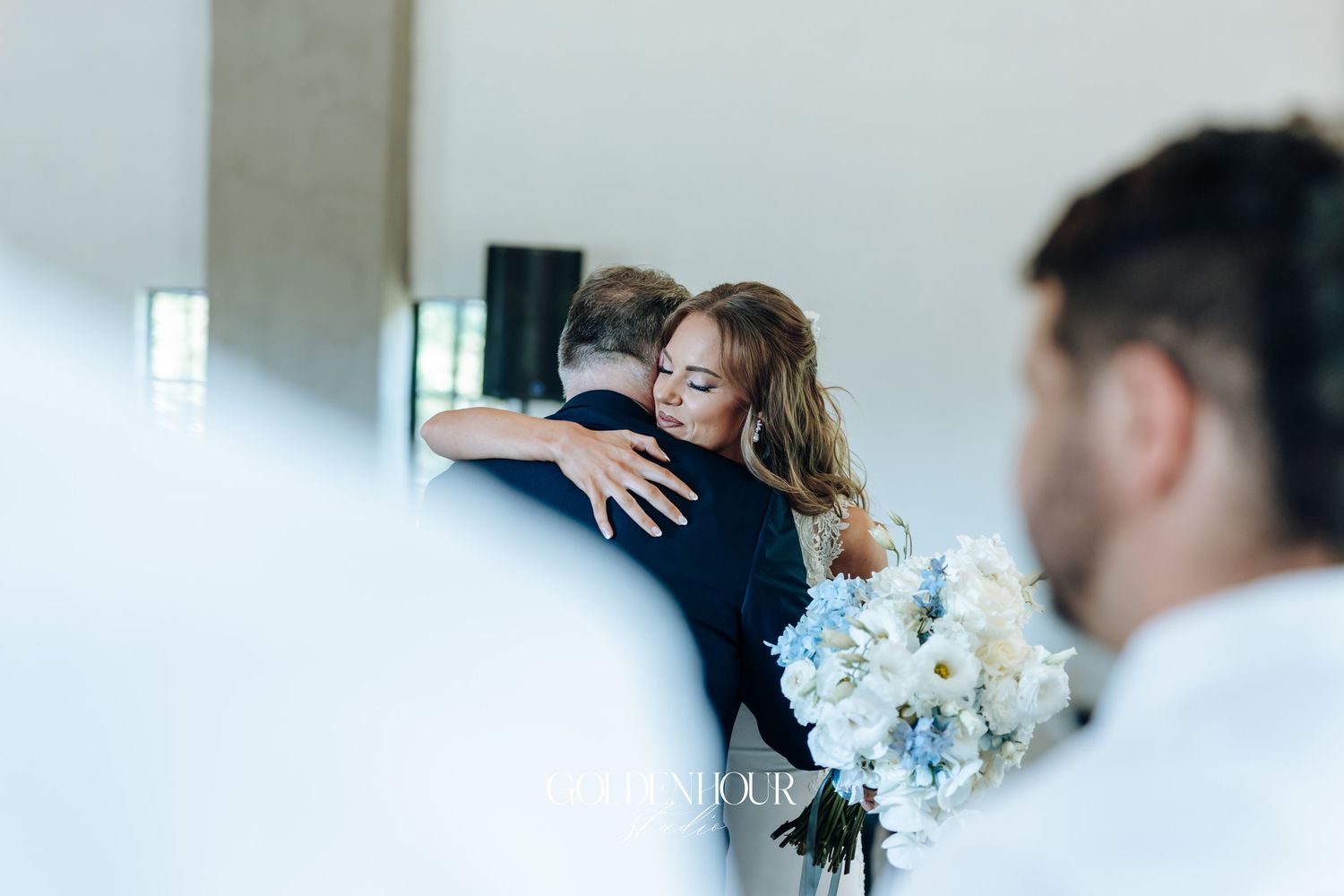 Wedding couple sharing an intimate moment during their first look in a bright indoor setting.
