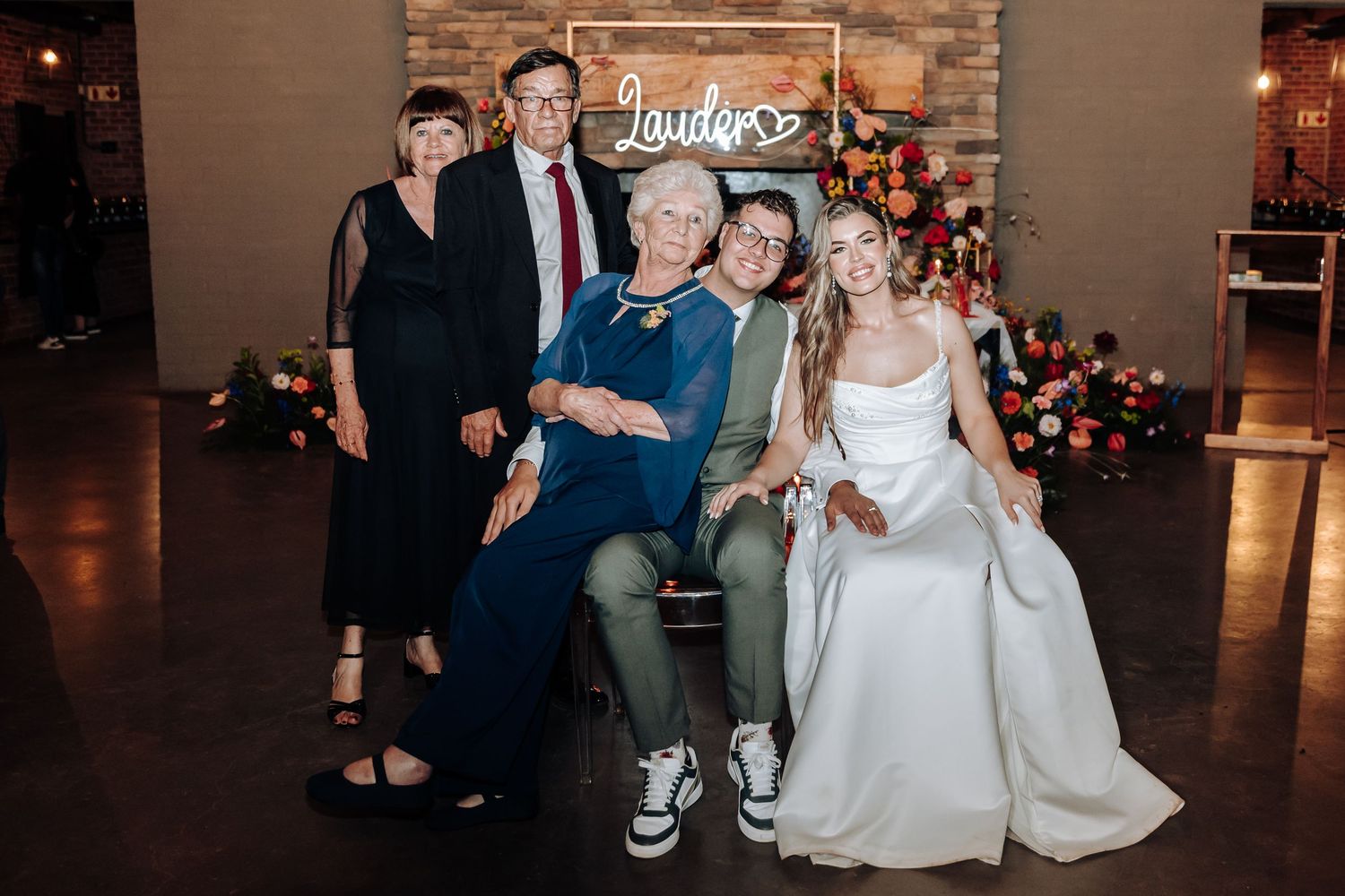 Wedding reception celebration with rustic brick wall backdrop and festive lighting.