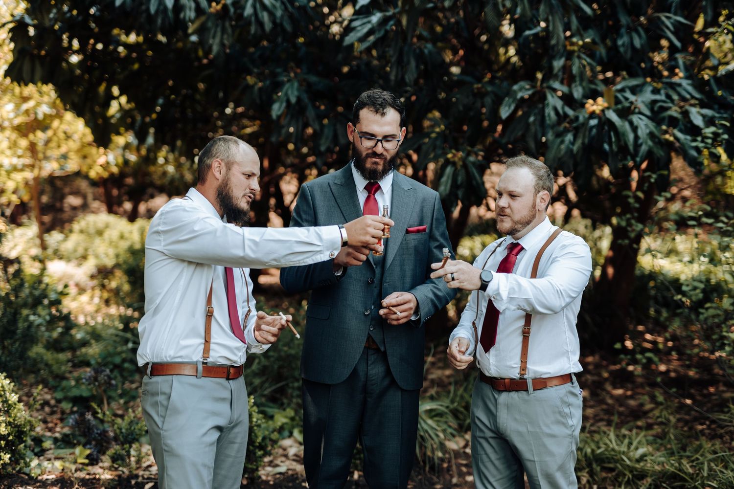 Wedding party members toasting with small Coca-Cola bottles in an outdoor garden setting.