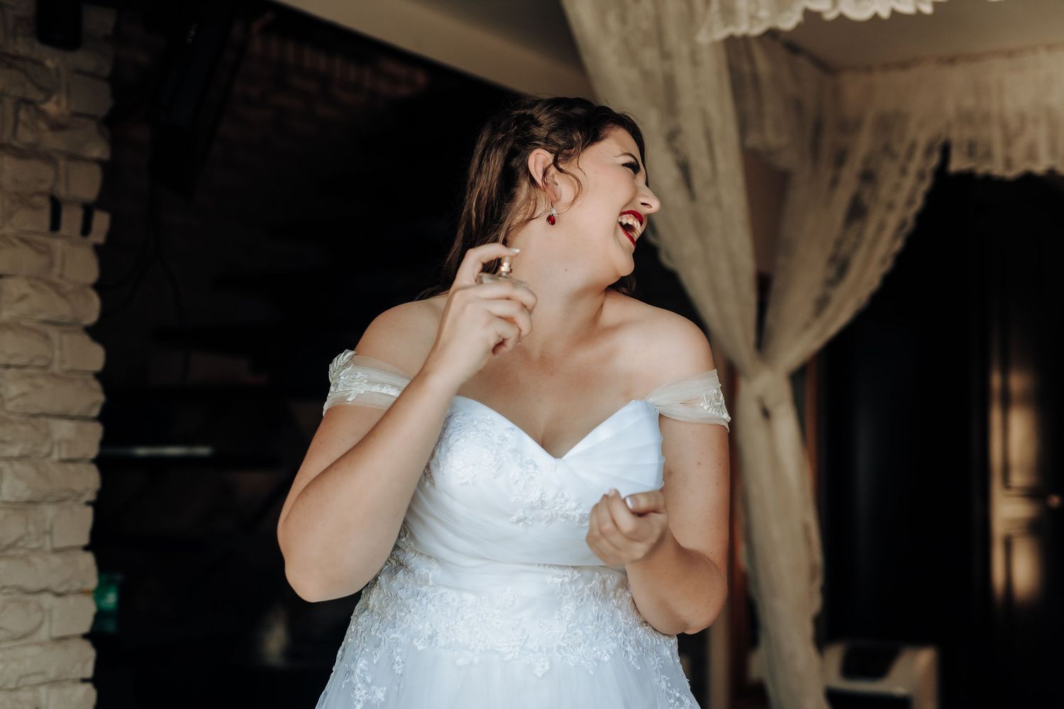 Joyful candid moment of a bride in white dress getting ready.