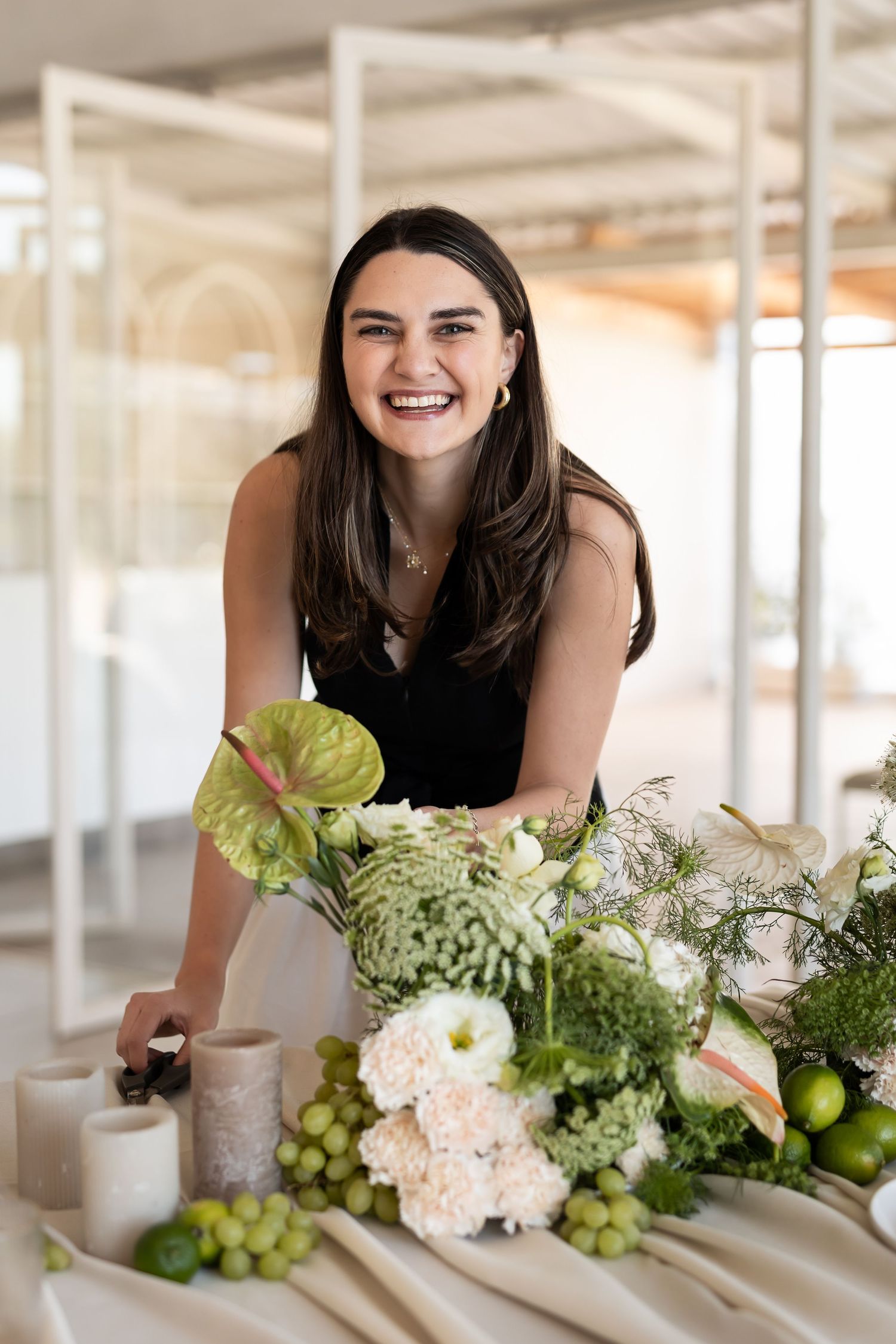 Three identical photos showing someone leaning over a decorative table display with white hydrangeas and green fruits.