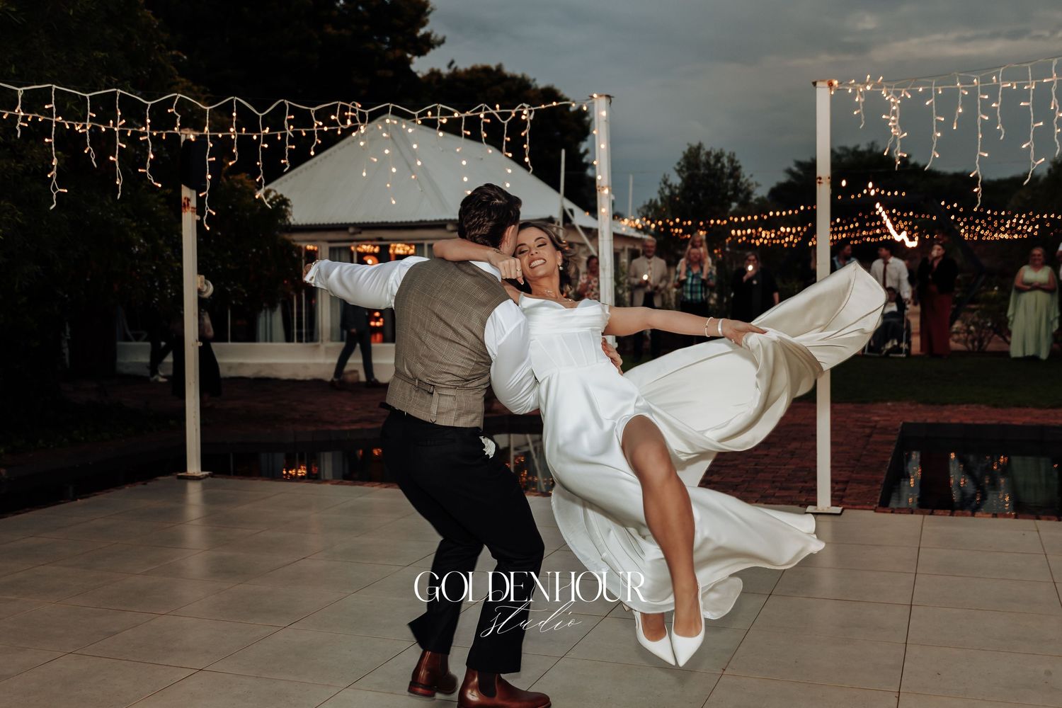 Wedding reception dance floor moments captured at dusk with string lights overhead.