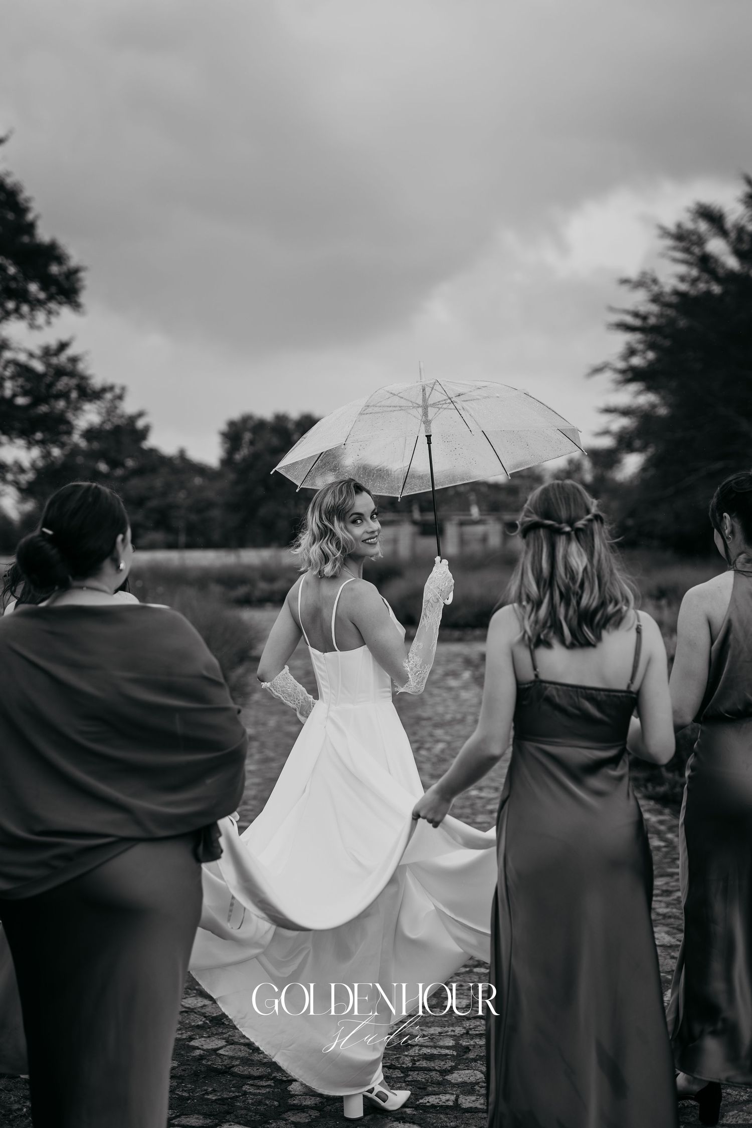 Black and white photo of bridal party walking together on rustic outdoor path.