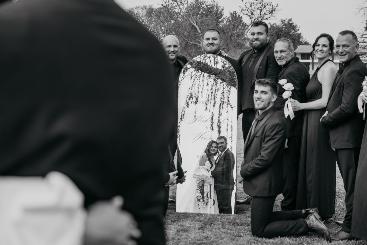 A series of black and white wedding photos showing joyful moments and embraces between couples and wedding guests.