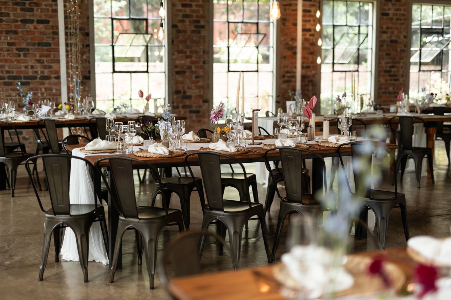 Industrial chic wedding reception venue with exposed brick walls and modern metal chairs.