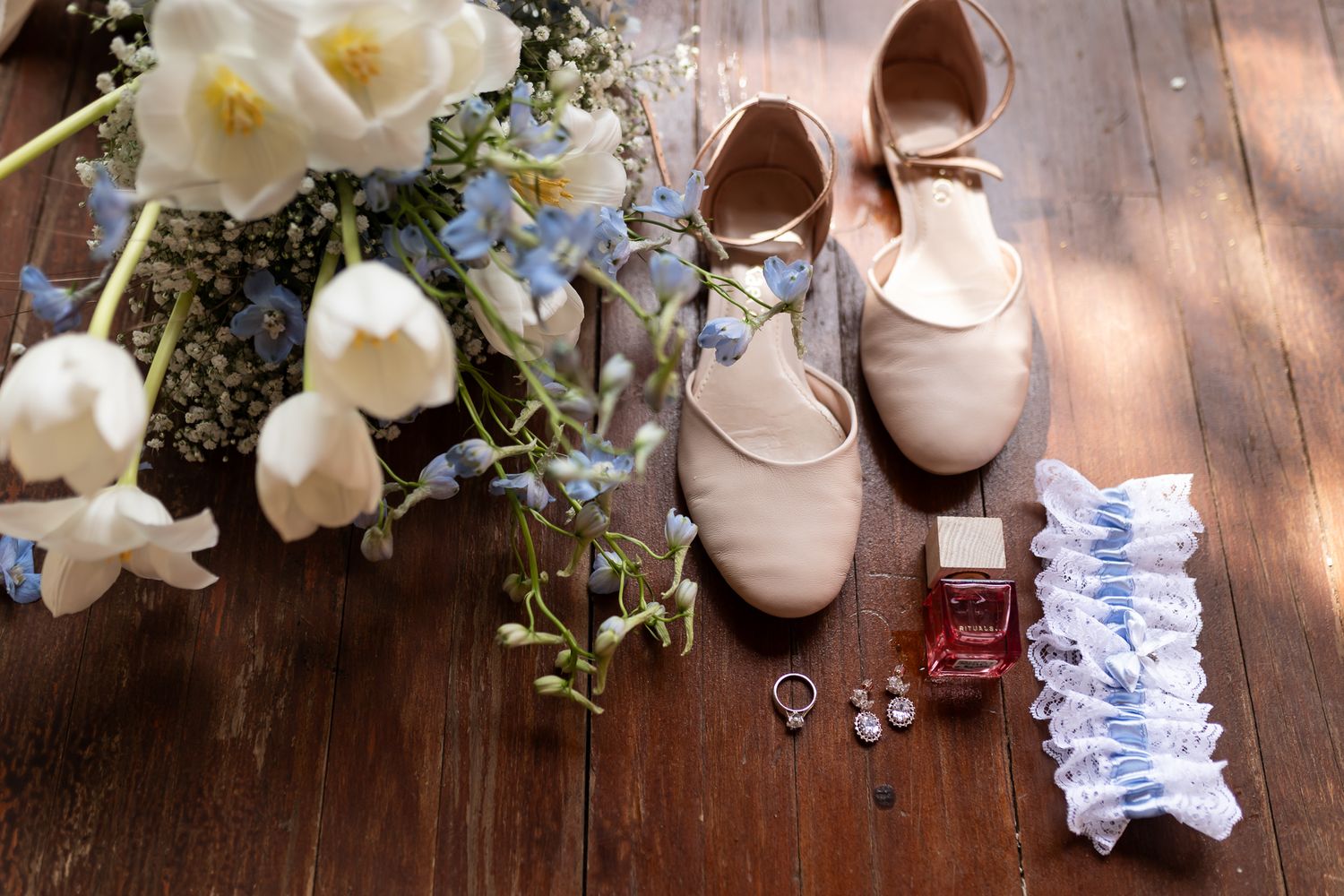 Bridal accessories including flowers, shoes, and jewelry arranged on wooden surface.