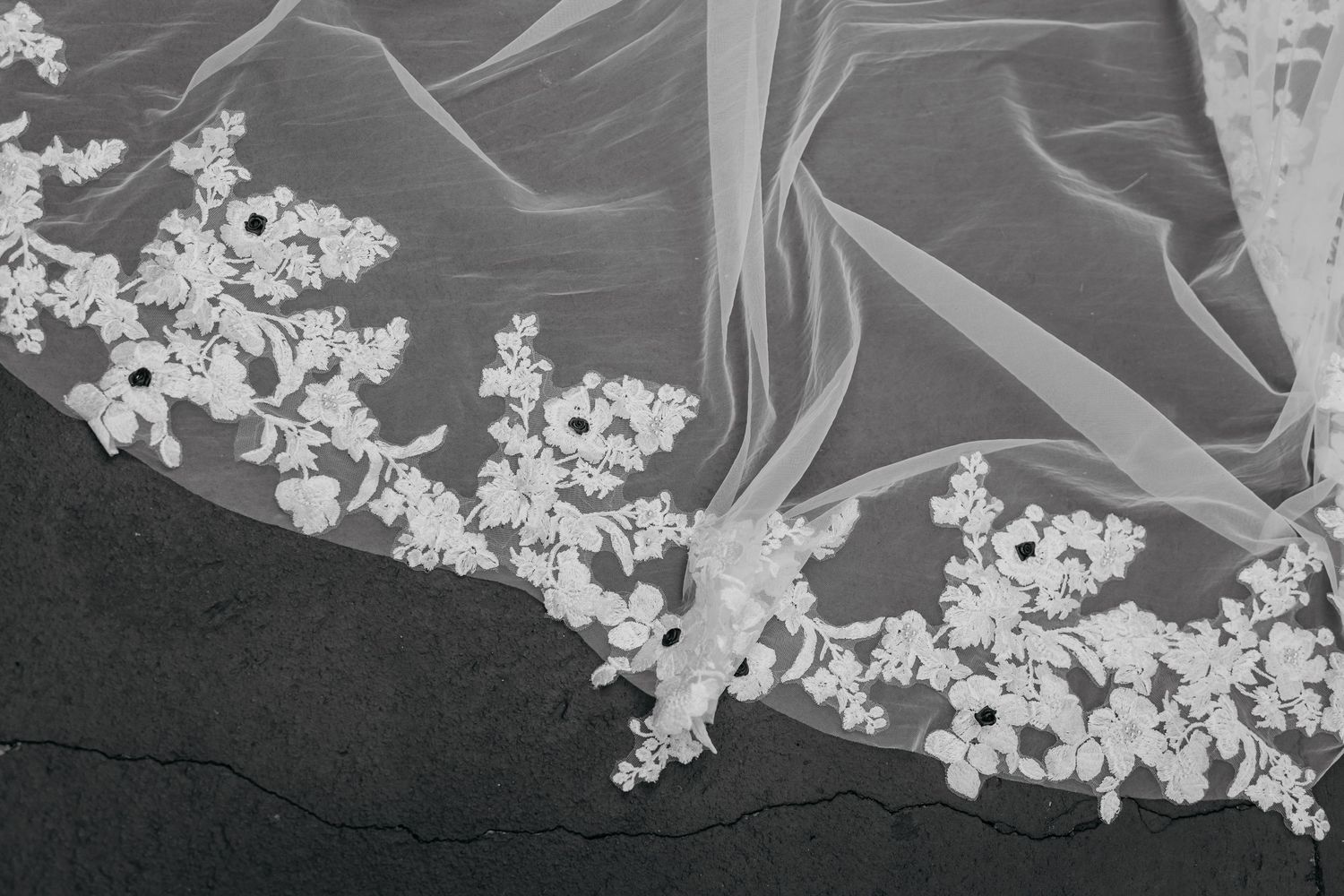 Detailed close-up of delicate floral lace embroidery on a white wedding veil.