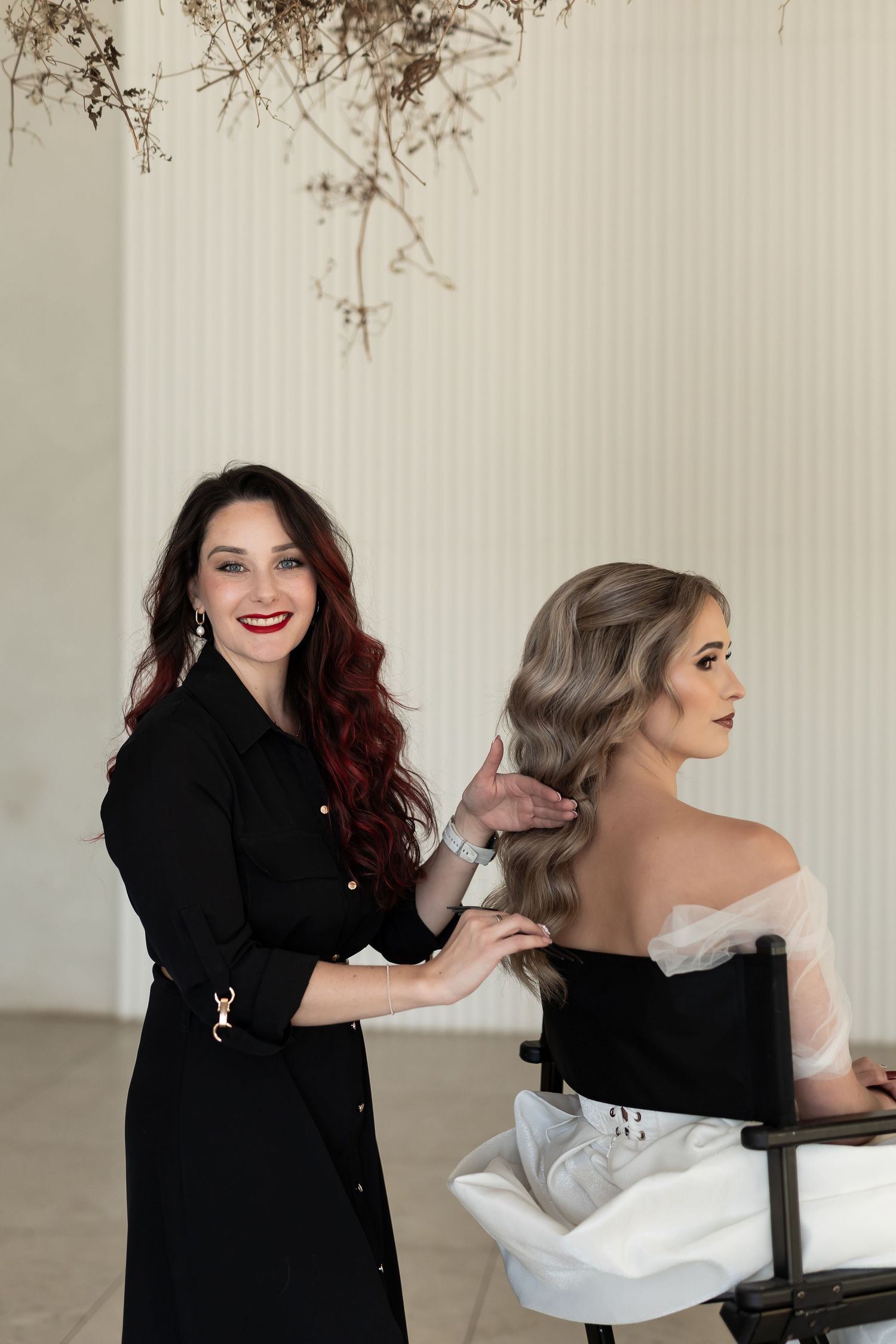 Two people in black and white outfits share a playful moment while posing together in a studio setting.