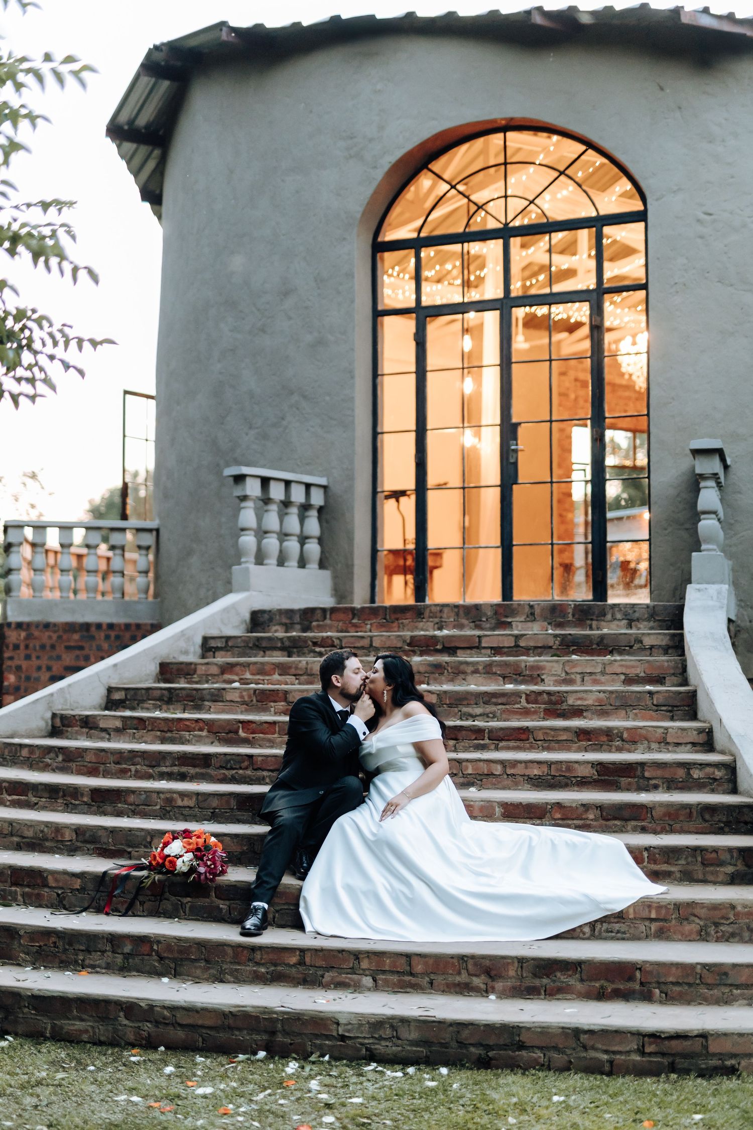 Artistic wedding portraits on stone steps featuring flowing white dress and architectural elements.