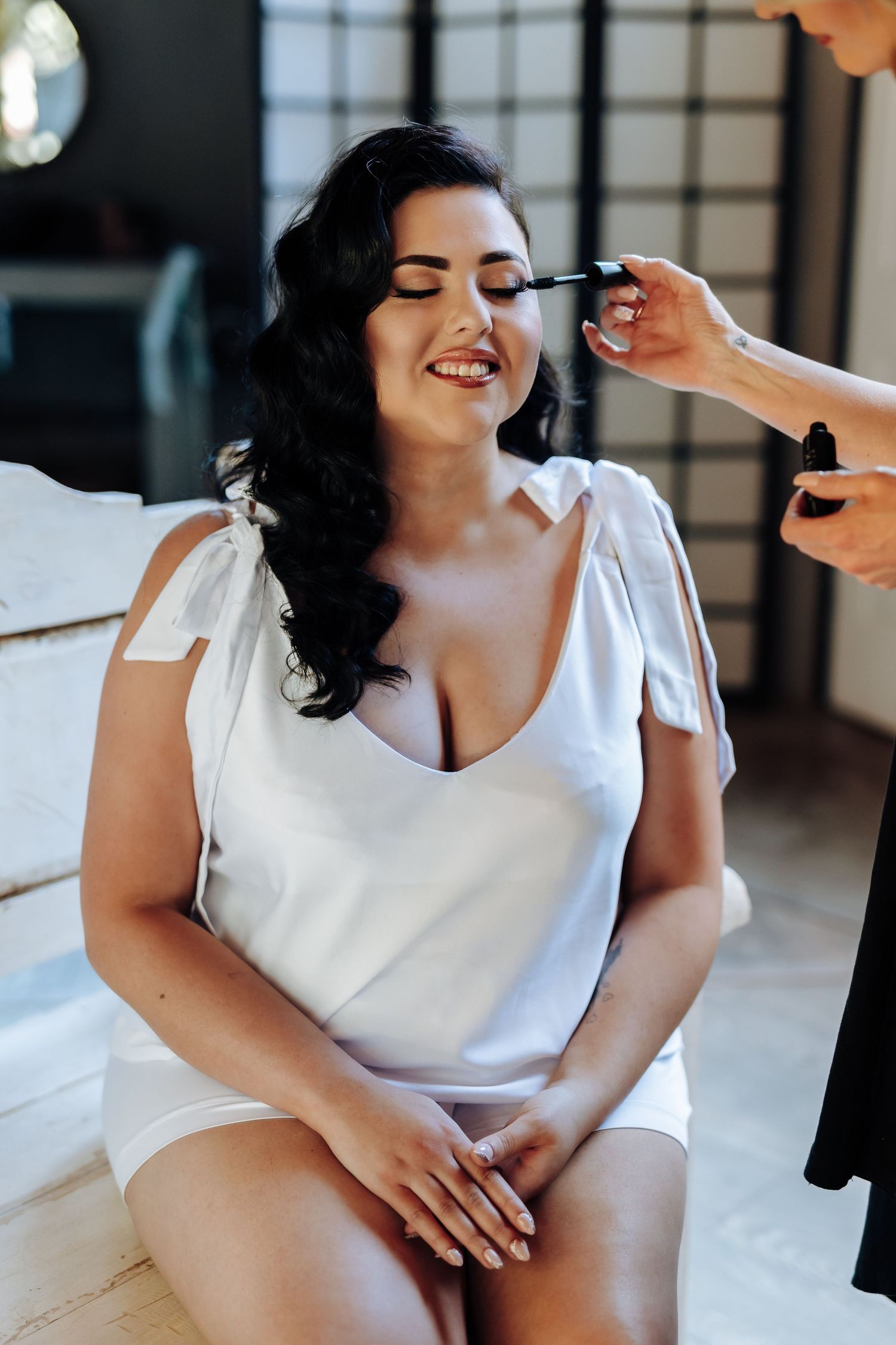 Wedding preparation scene with makeup being applied in a bright indoor setting.