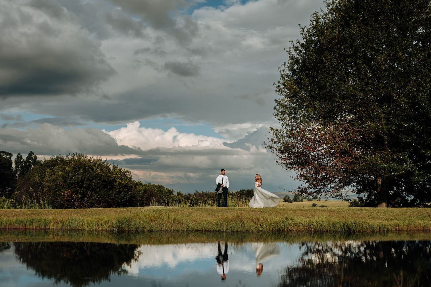 A dramatic panoramic view of a rural landscape with trees, fields and moody clouds stretching across the horizon.