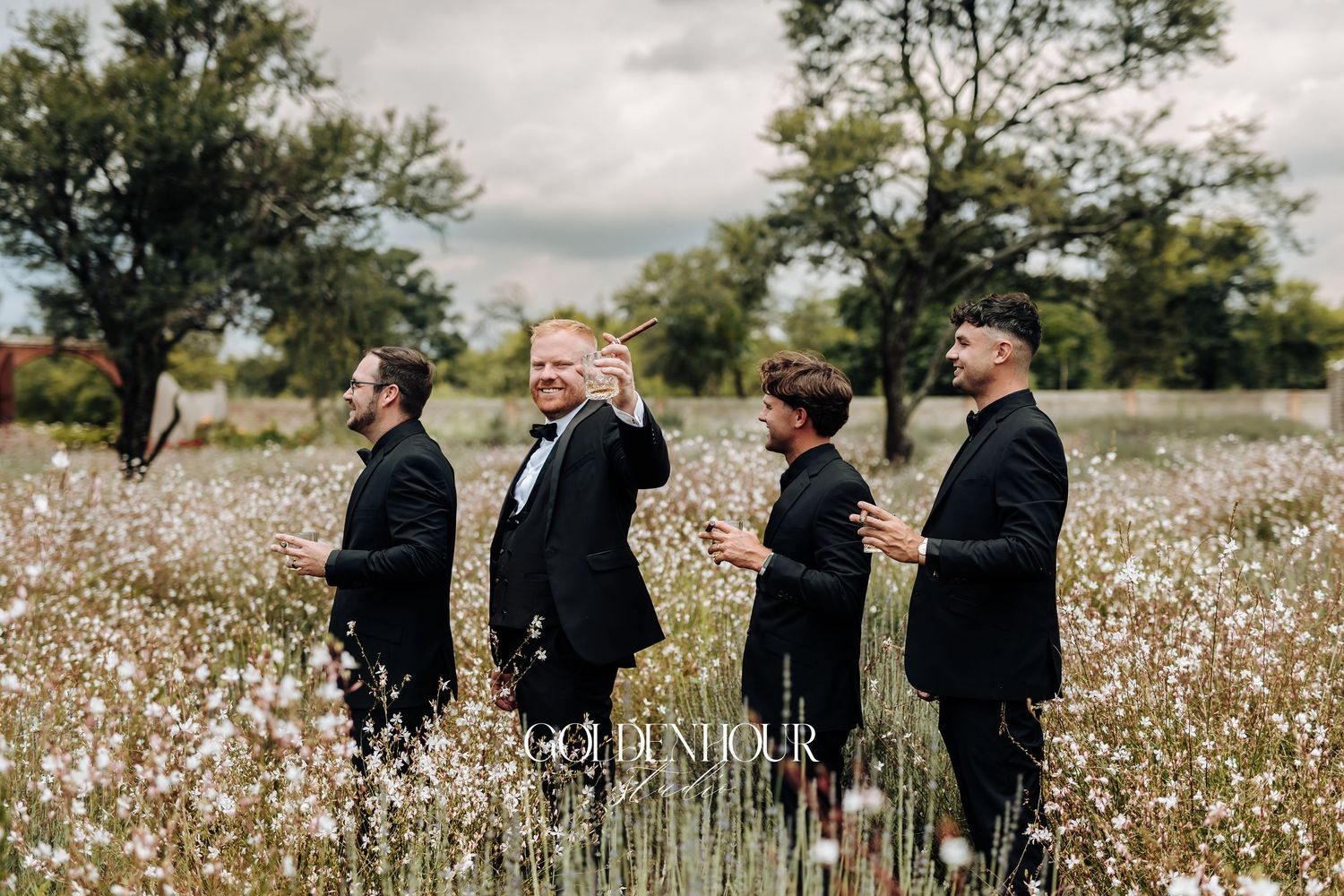 People in formal attire walking through a blooming cotton field on an overcast day.