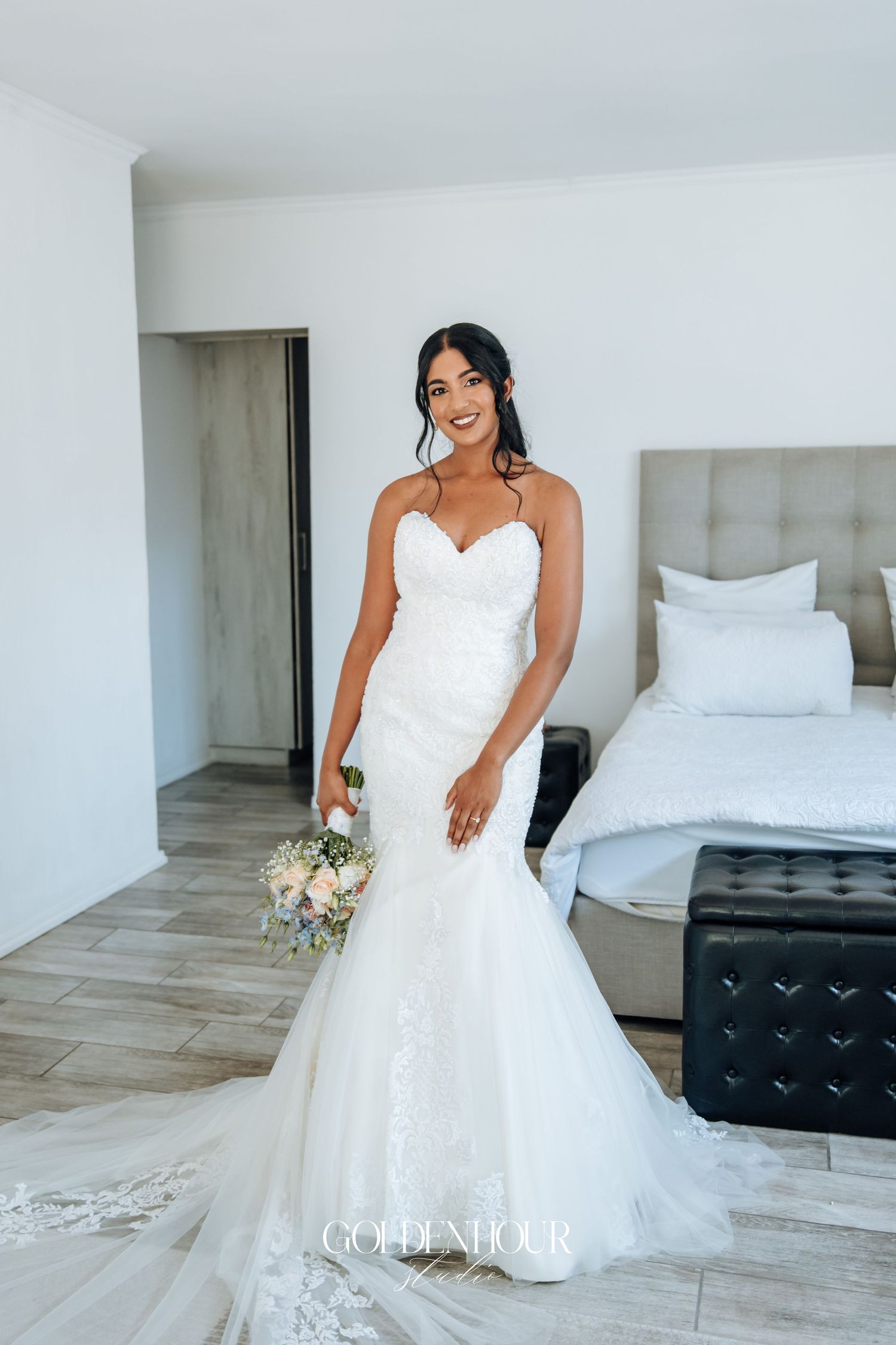 Elegant bride in a white strapless ballgown poses in a bright modern room.