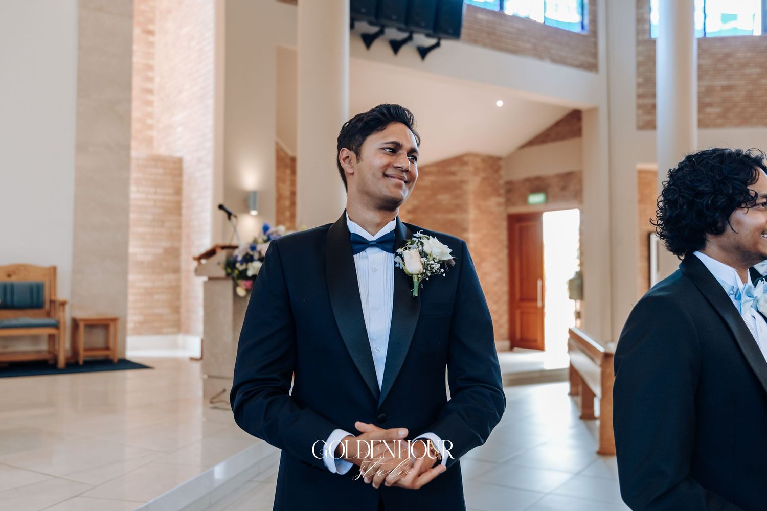 Groomsmen in formal attire gather in spacious church corridor before ceremony.