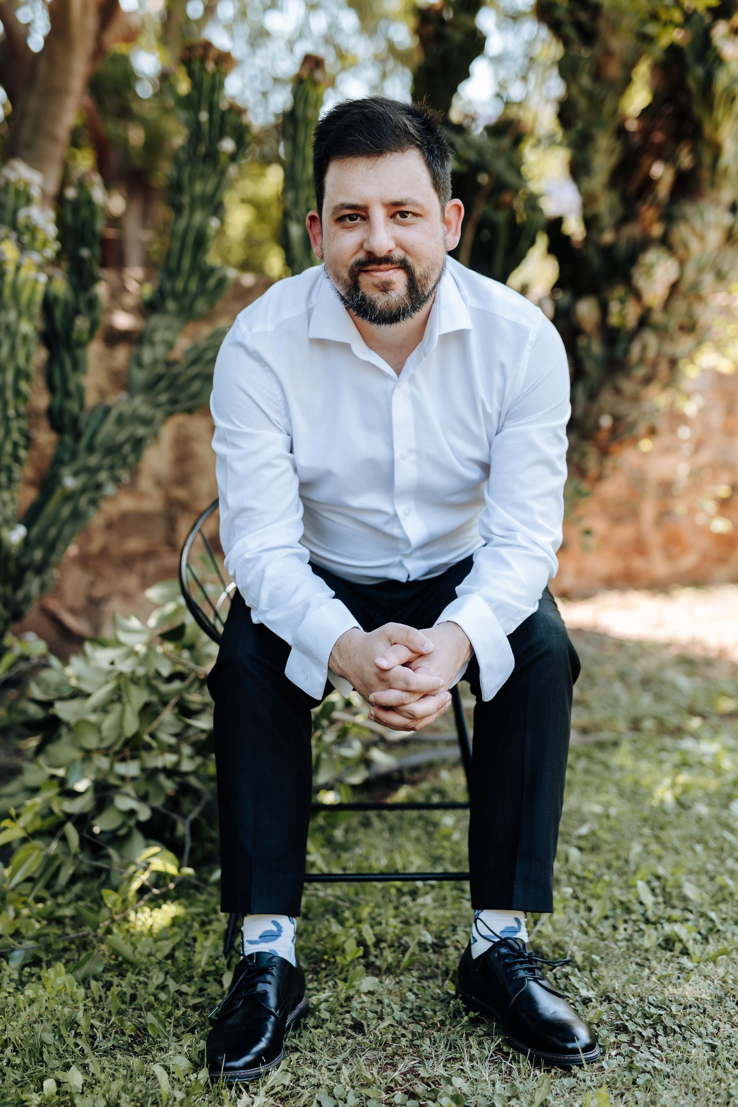 White dress shirt and black pants detail with polished shoes on grass in outdoor setting.
