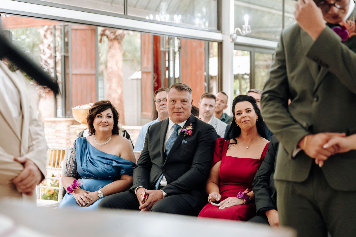 Wedding guests hold hands in an intimate moment during an outdoor ceremony.