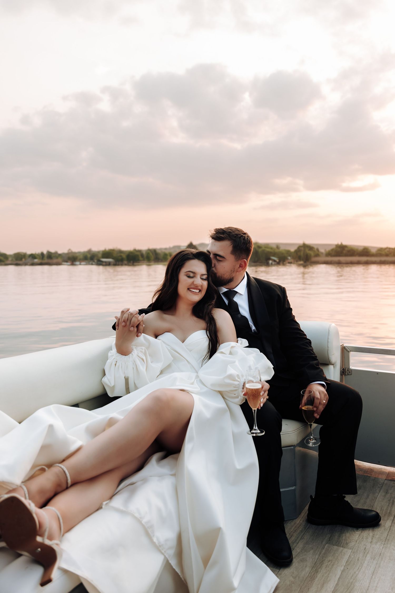 A couple shares romantic moments on a boat at sunset while enjoying champagne and intimate conversation.