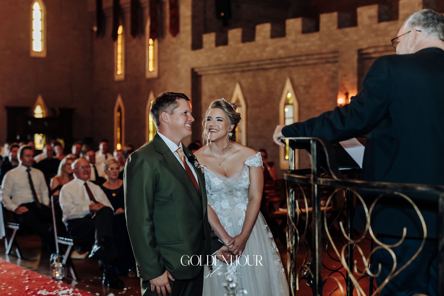 Bride and groom stand smiling at altar during wedding ceremony inside a historic church venue.