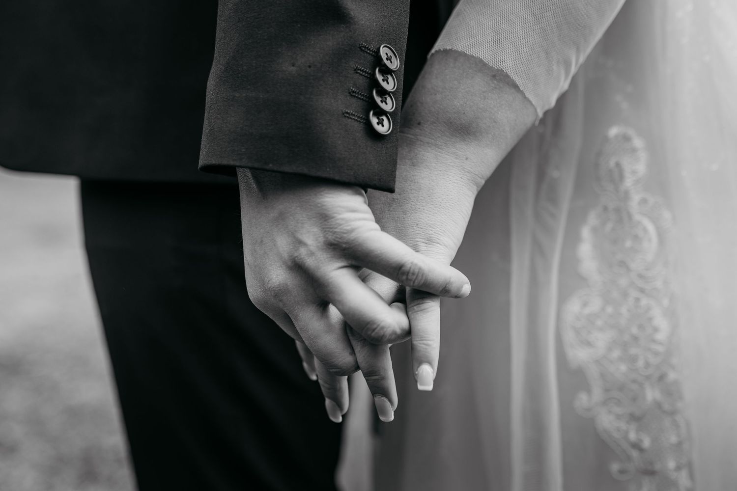 Black and white wedding details showing hands holding bouquets with elegant ring details.