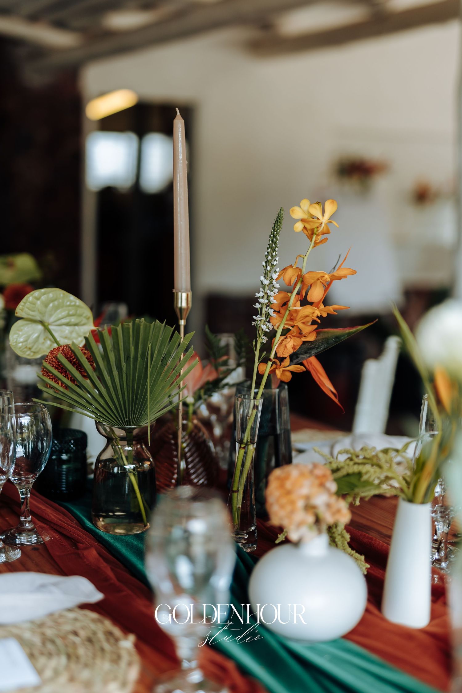 Elegant wedding table settings with tropical palm leaves, orange flowers, and white candles create a modern romantic atmosphere.