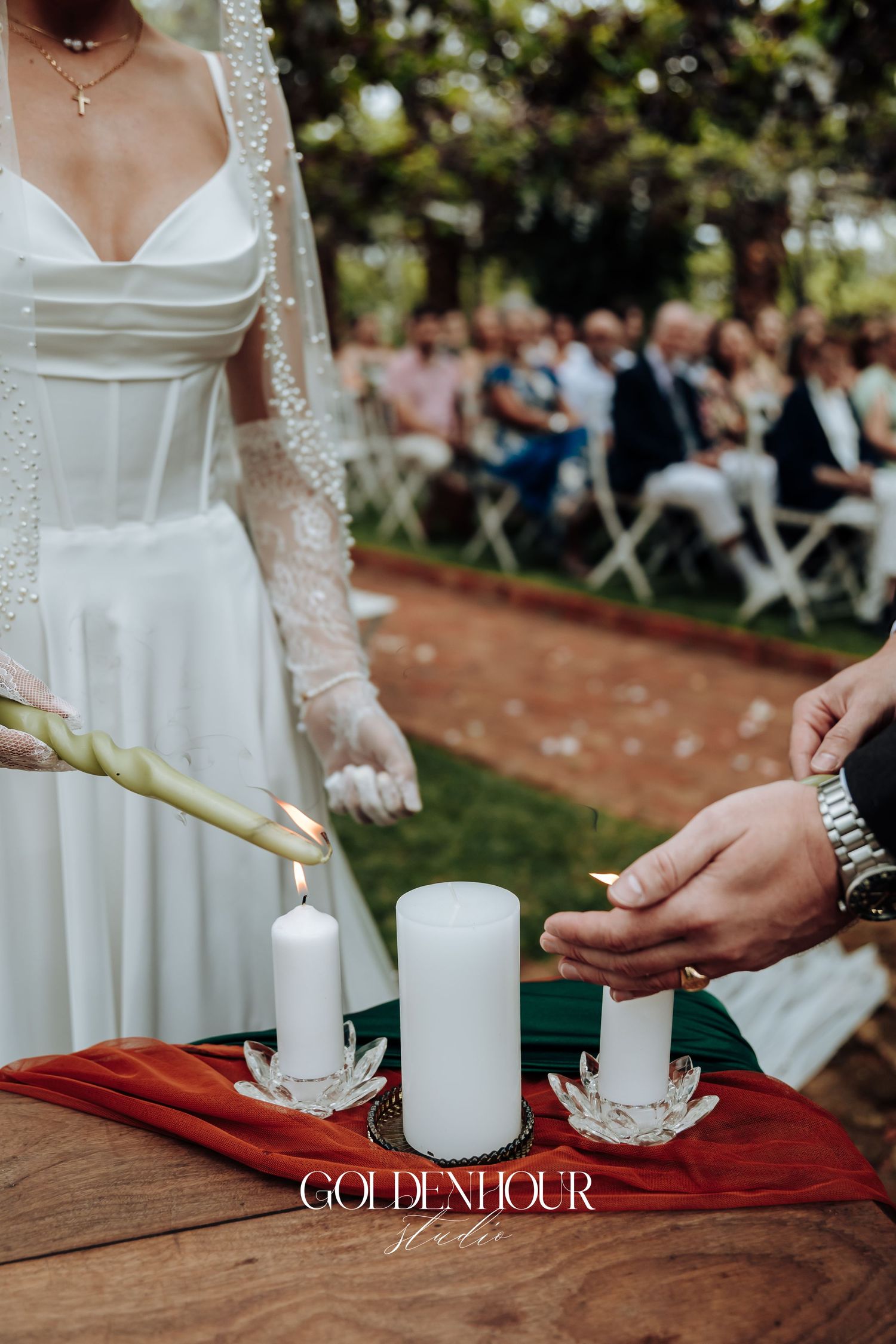 White candles being lit during outdoor wedding unity ceremony.