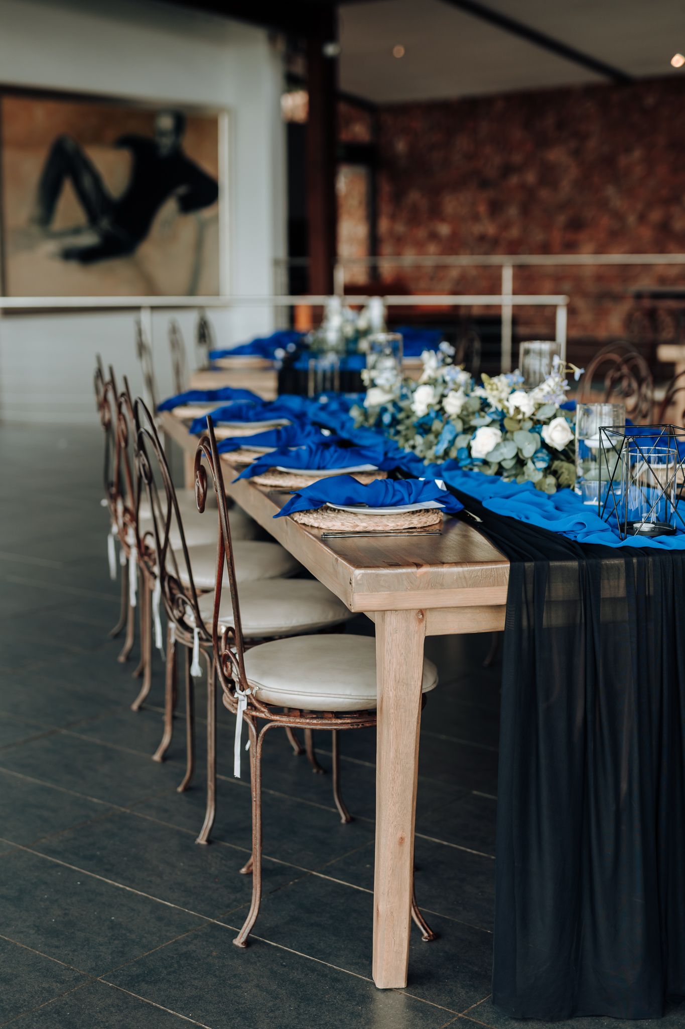 Elegant wedding reception table with royal blue runner and copper chairs.