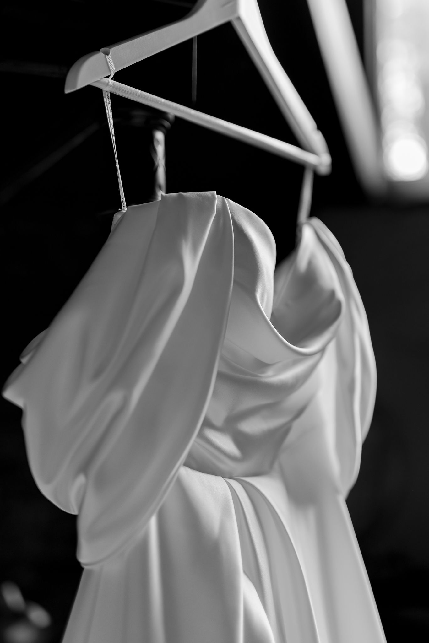 Close-up black and white photo of wedding dress fabric details on hanger.