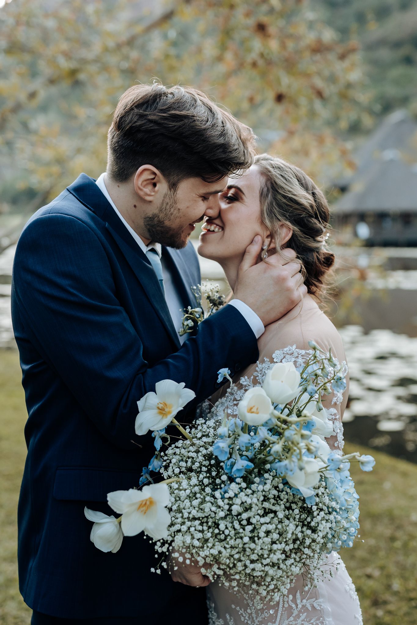 Romantic wedding moment captured with white floral bouquet against scenic lakeside setting.