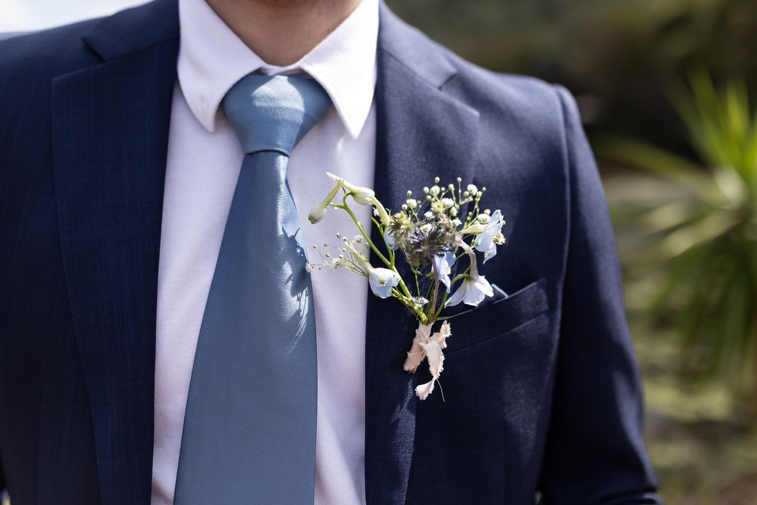 Close-up of blue boutonniere and tie on navy suit lapel.