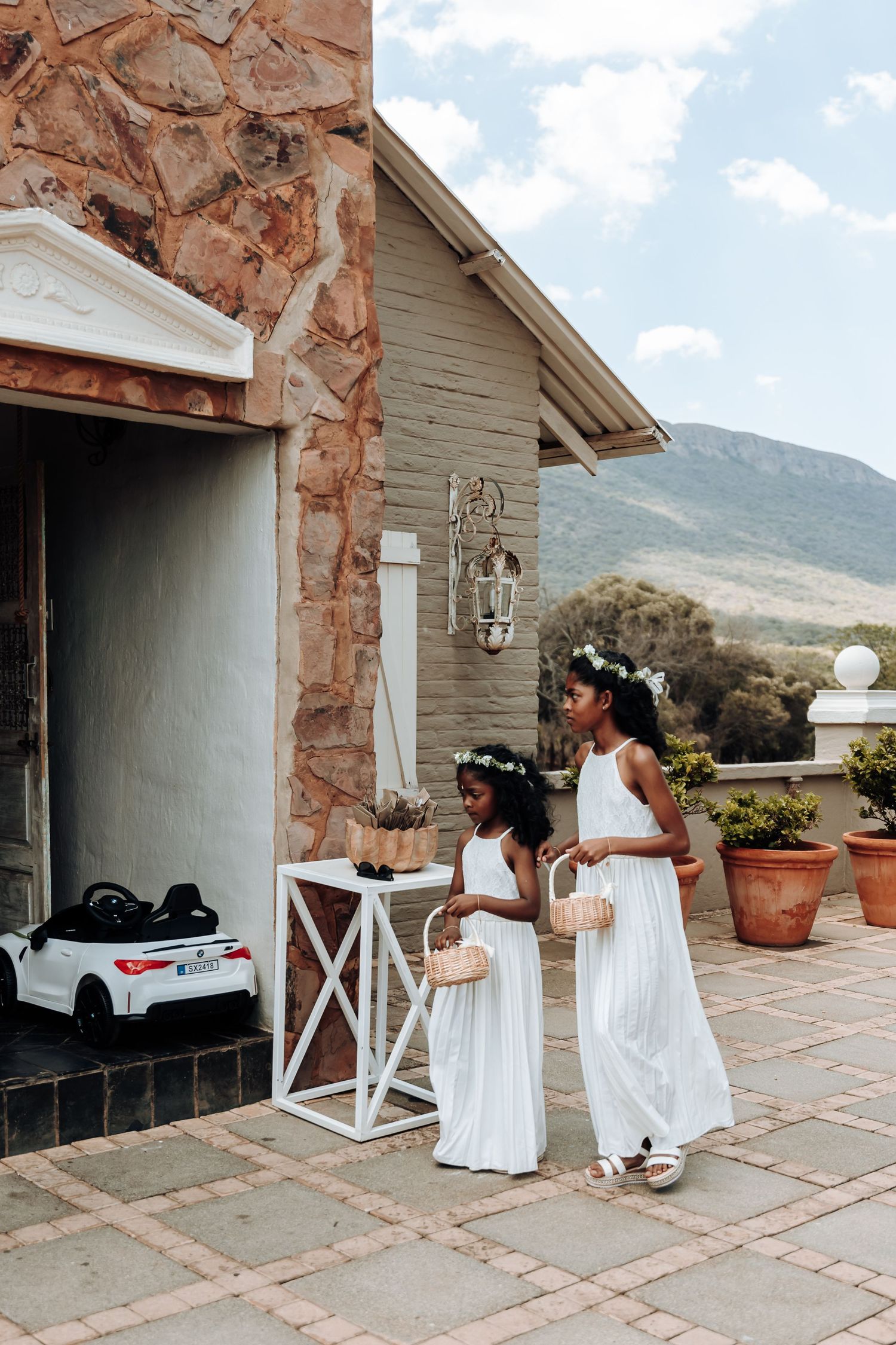White dresses against stone exterior of building with mountains in background.