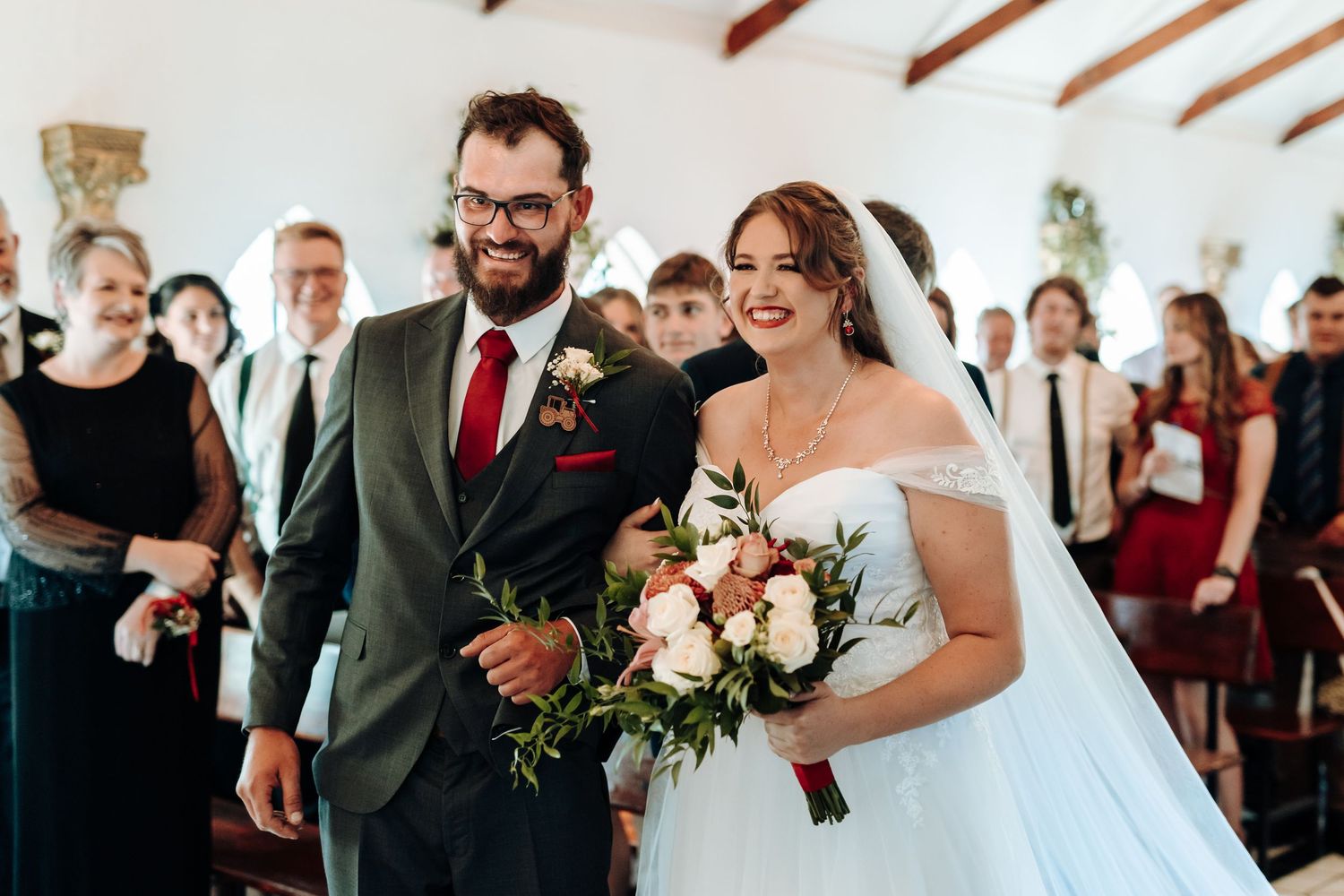Happy couple sharing moment during wedding ceremony in chapel with exposed beams.