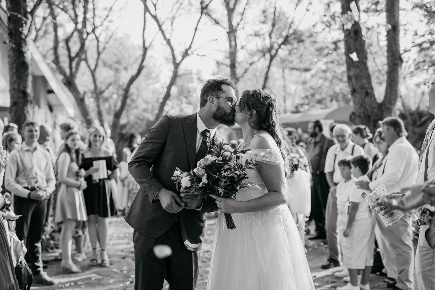 A black and white photo captures an intimate moment between newlyweds during their outdoor ceremony.