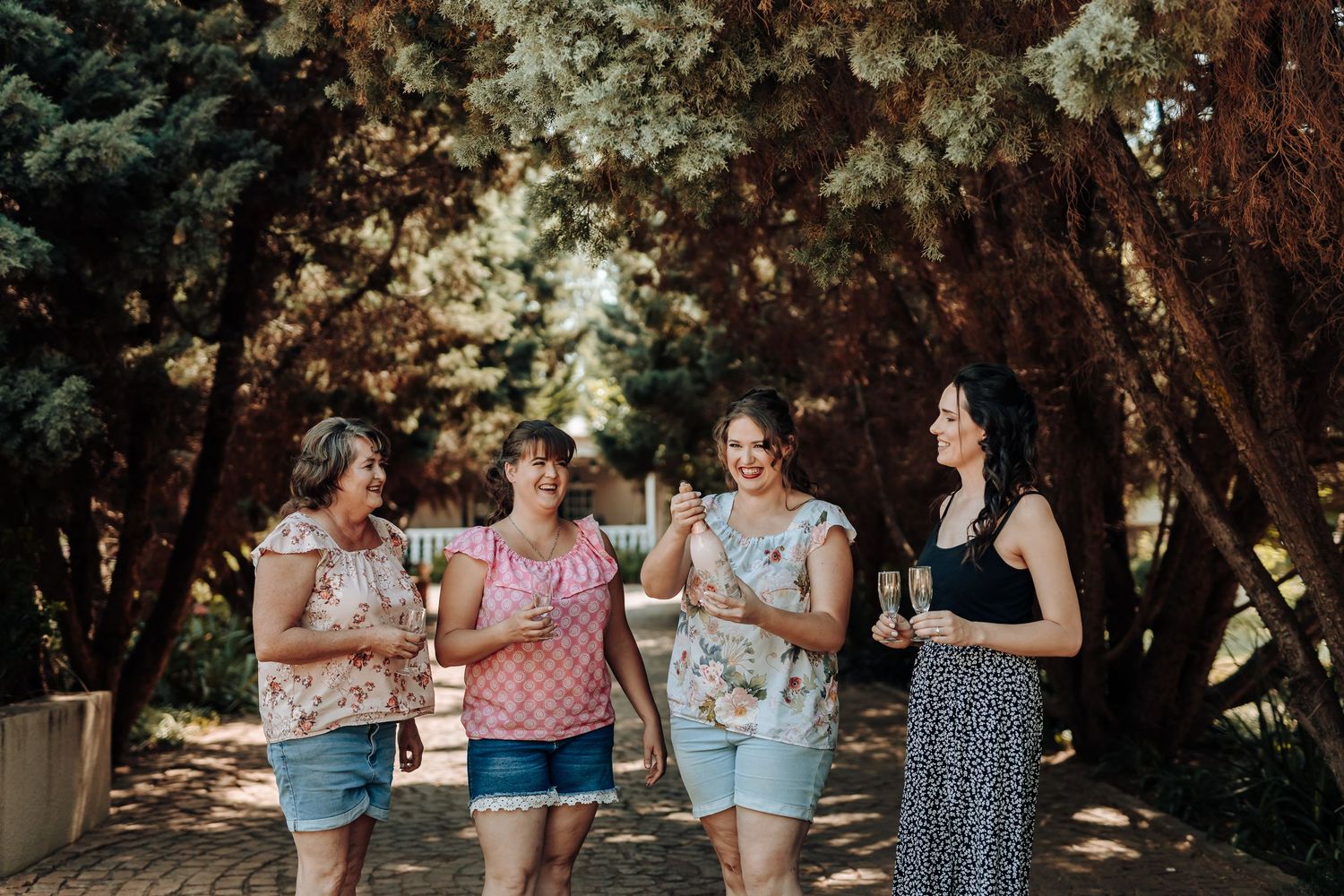 Group of friends laughing while walking through wooded path.