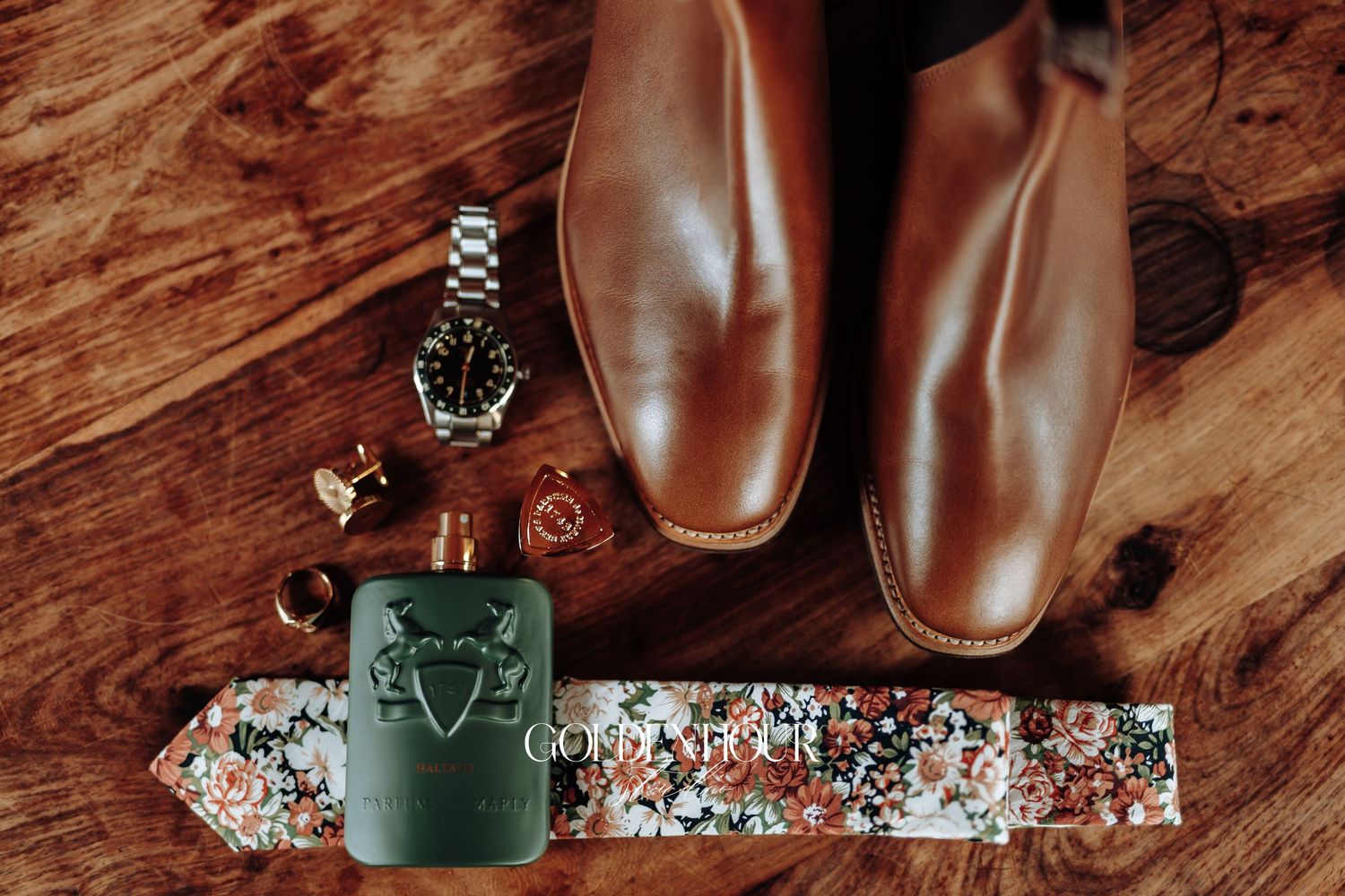A collection of brown leather boots and shoes arranged on a rustic wooden surface with a green coffee mug.