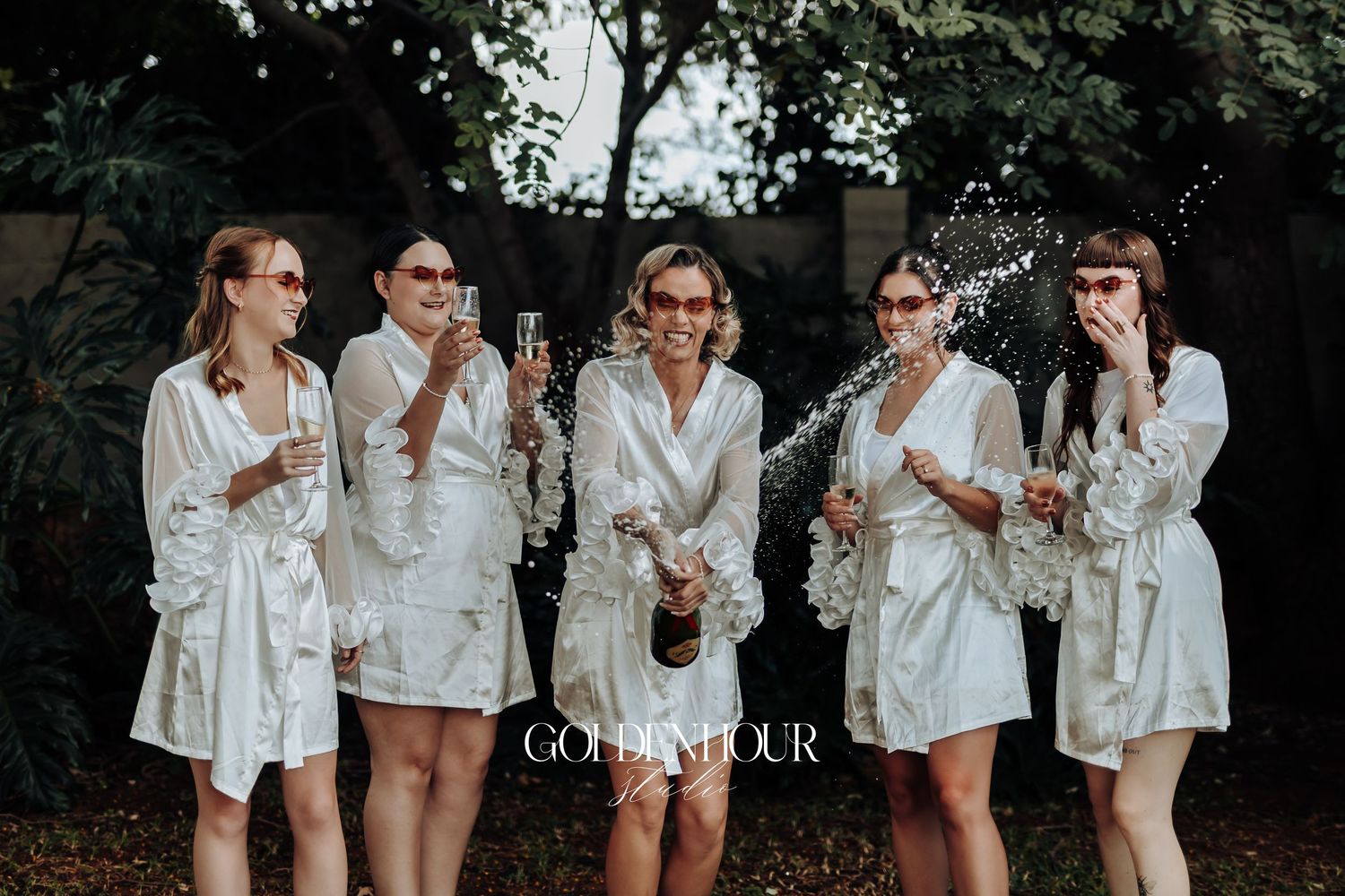 Wedding party members in white robes laughing together during pre-ceremony preparations.