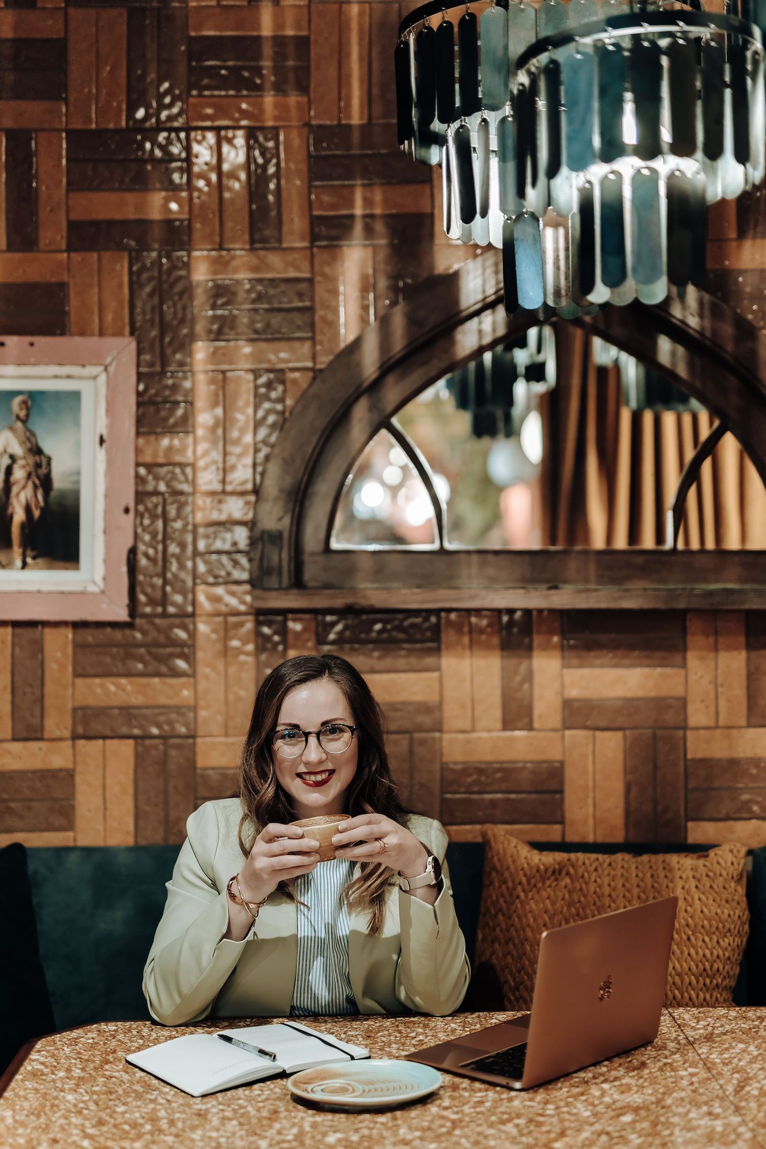 Coffee shop interior features cozy lighting, brown patterned decor, and warm ambiance with a laptop setup.