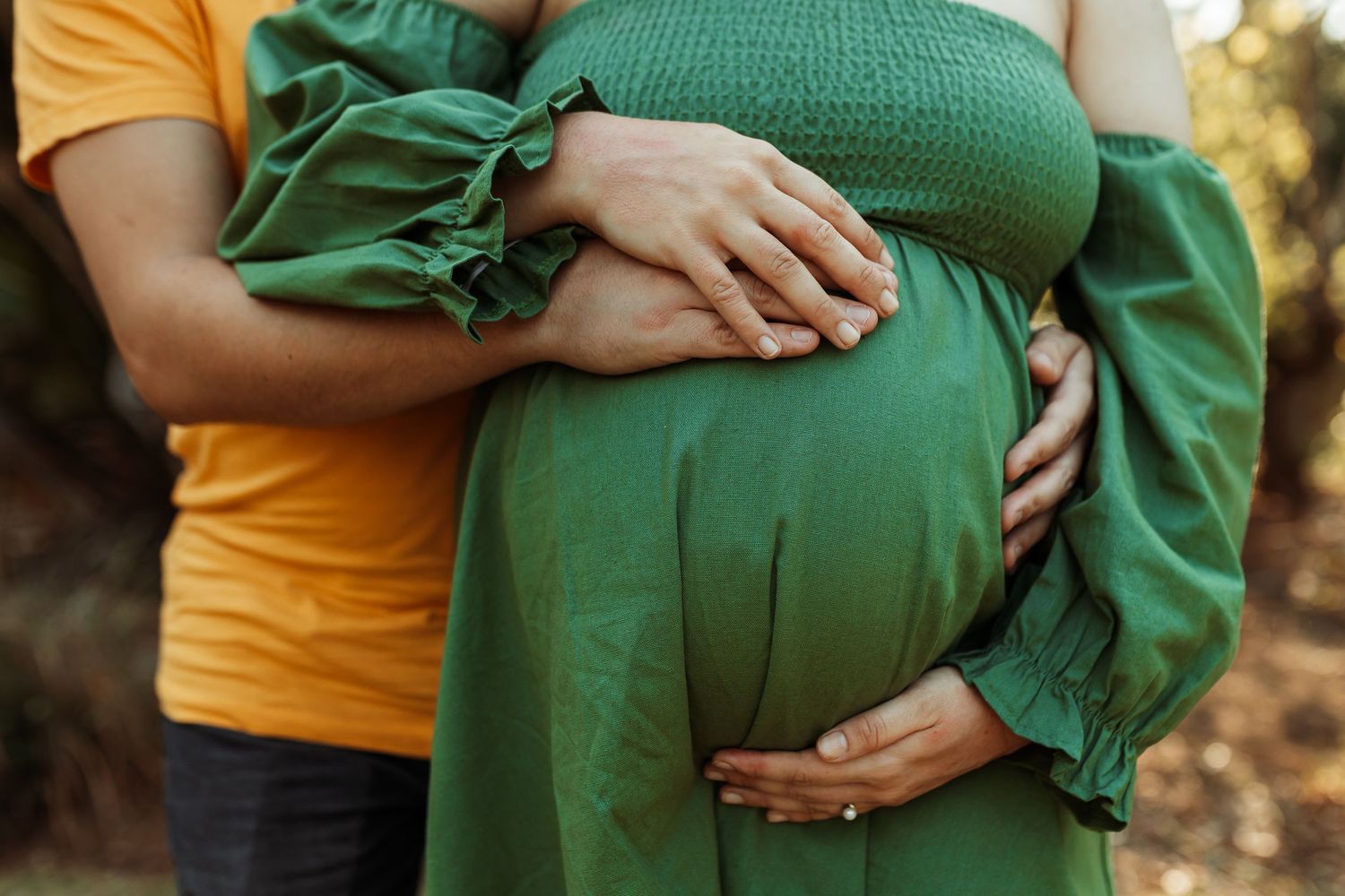 A series of close-up photographs showing hands cradling a pregnant belly in a green maternity dress against a natural backdrop.