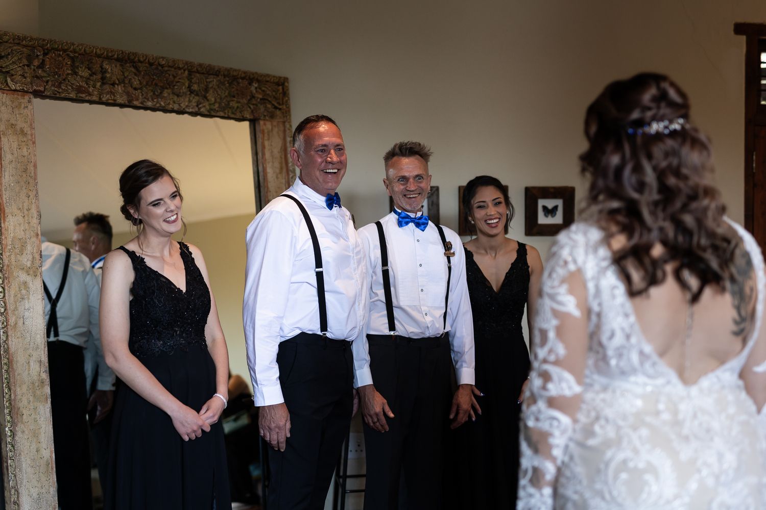 Wedding party in formal black and white attire stands together during pre-ceremony moments.