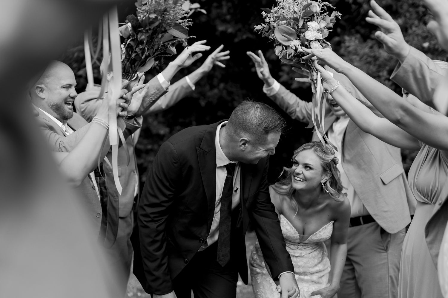 Black and white candid moment of wedding celebration with raised hands.