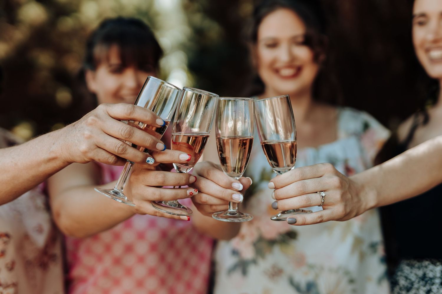 Close-up of champagne glasses clinking together in a celebratory toast outdoors.