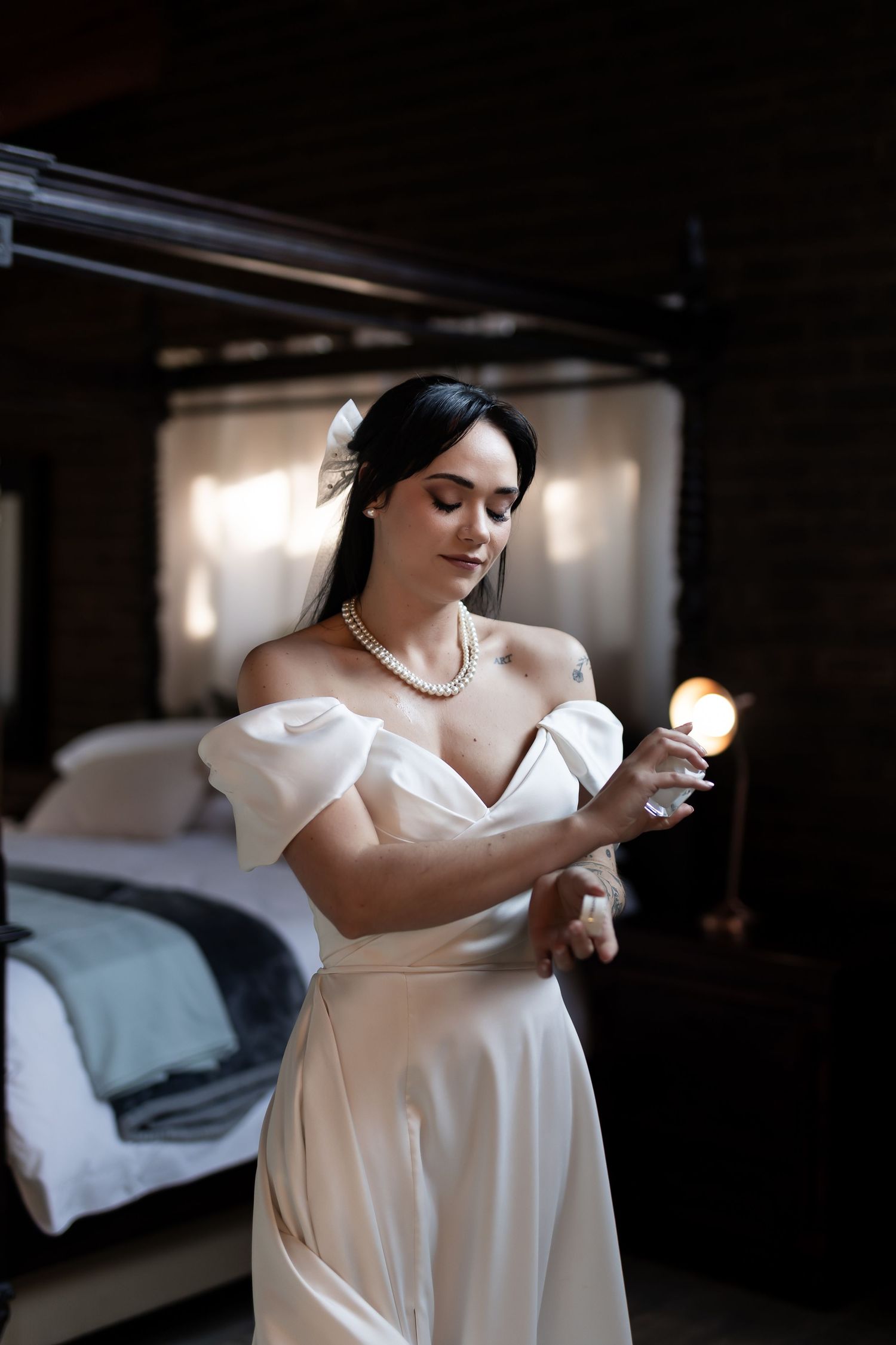 A figure in a flowing white dress stands elegantly in moody lighting against a dark background.