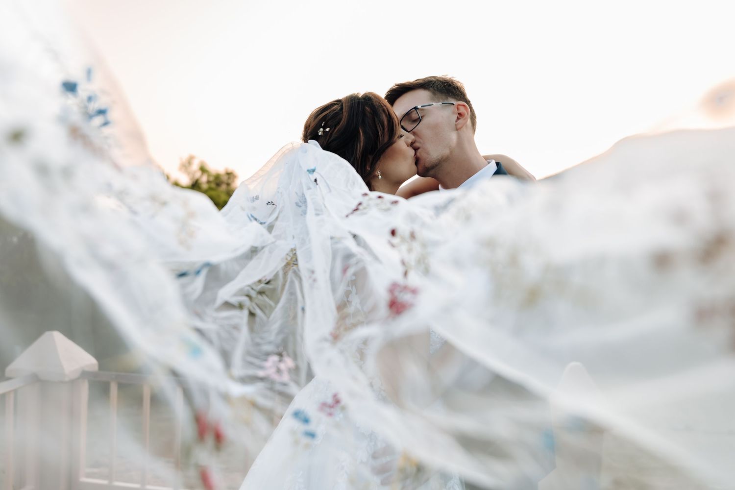 A close-up view of white fabric with delicate floral patterns blowing in the breeze.
