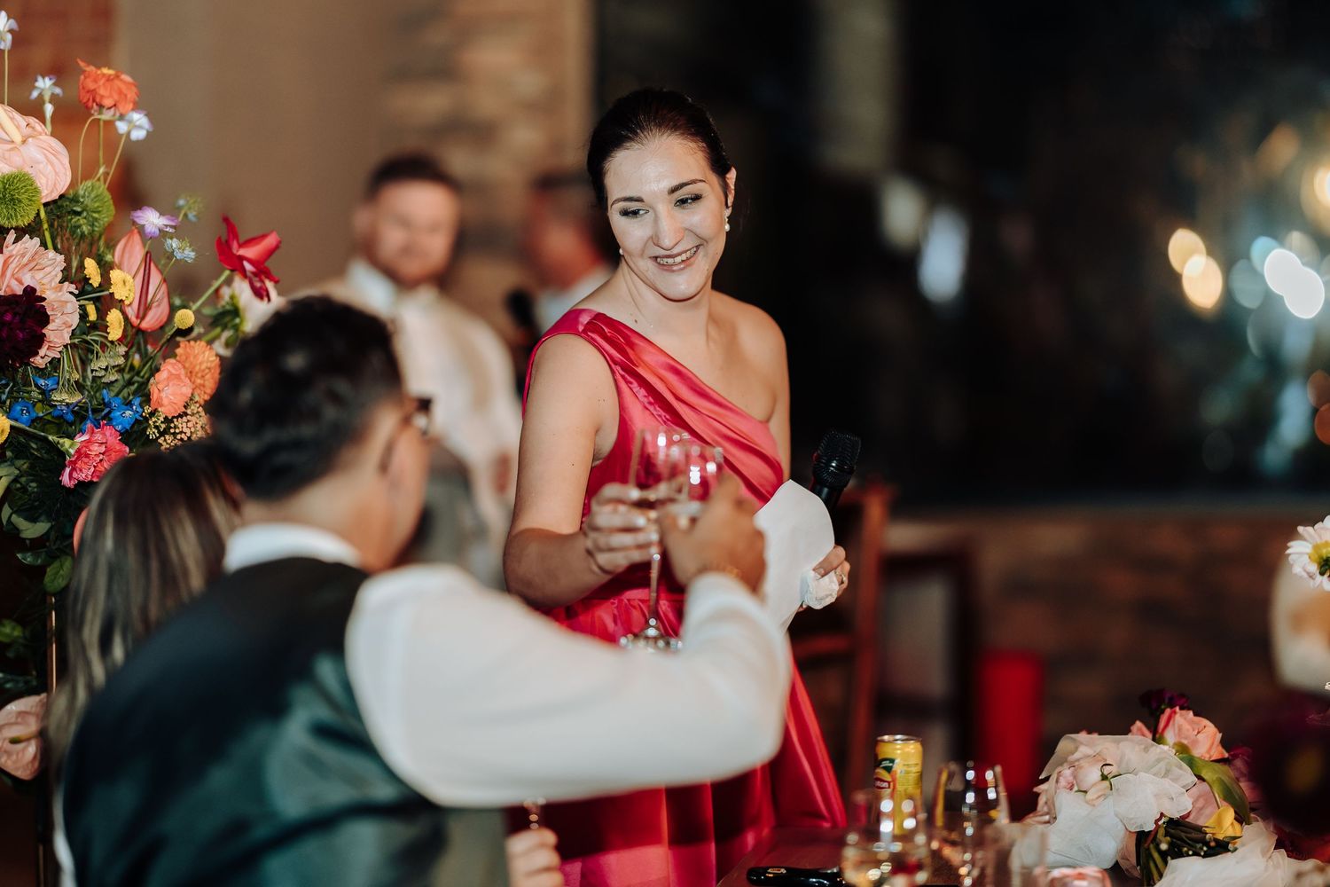 Wedding reception guests interact at an elegantly decorated table with floral arrangements and candlelight.