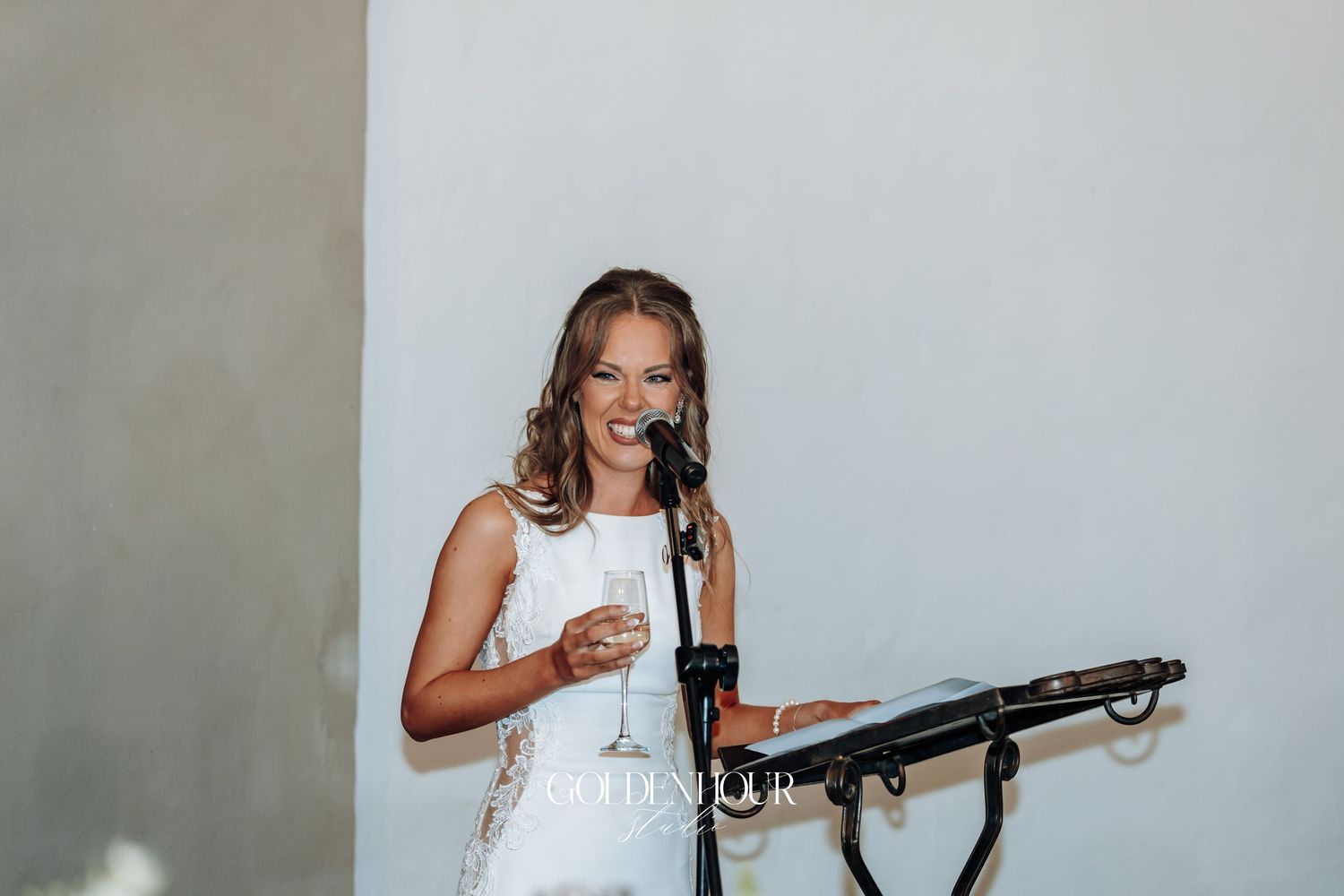 A wedding reception speech moment with microphone against a light background.