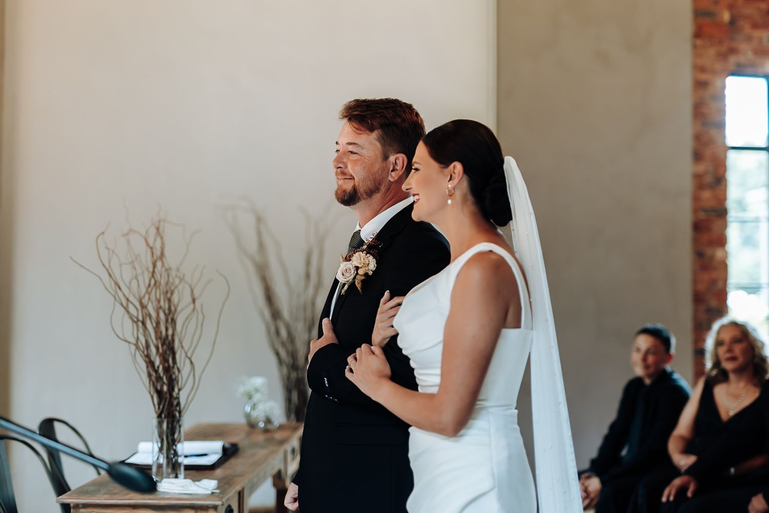 Intimate wedding ceremony scene in a modern venue with exposed brick walls and natural lighting.