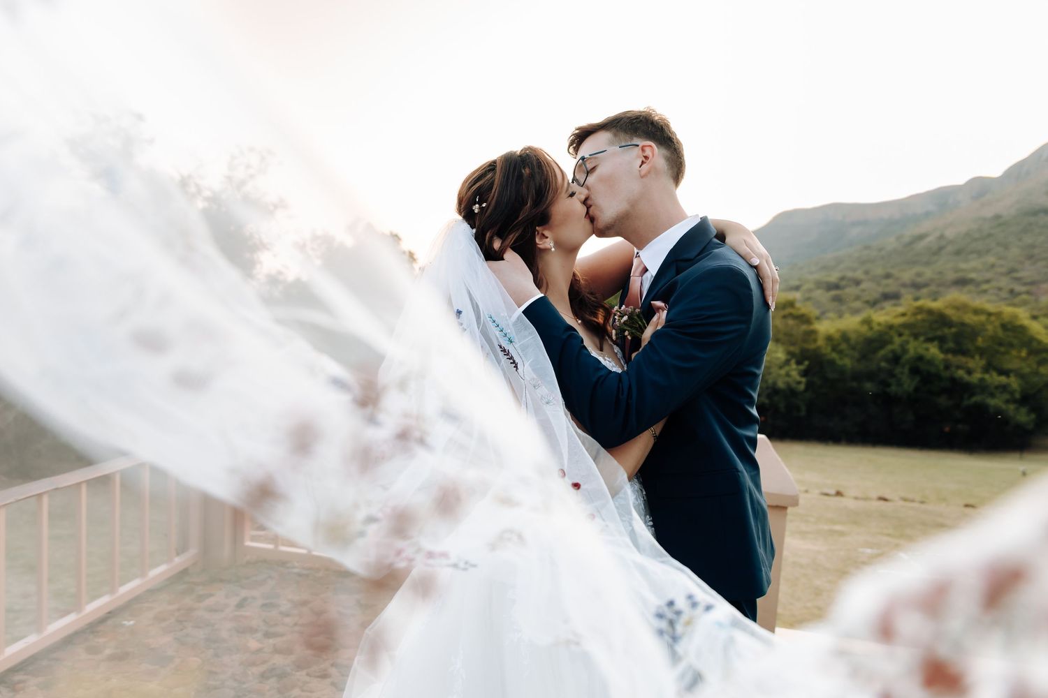 Romantic couple embracing in a misty mountain landscape during a dreamy outdoor photoshoot.