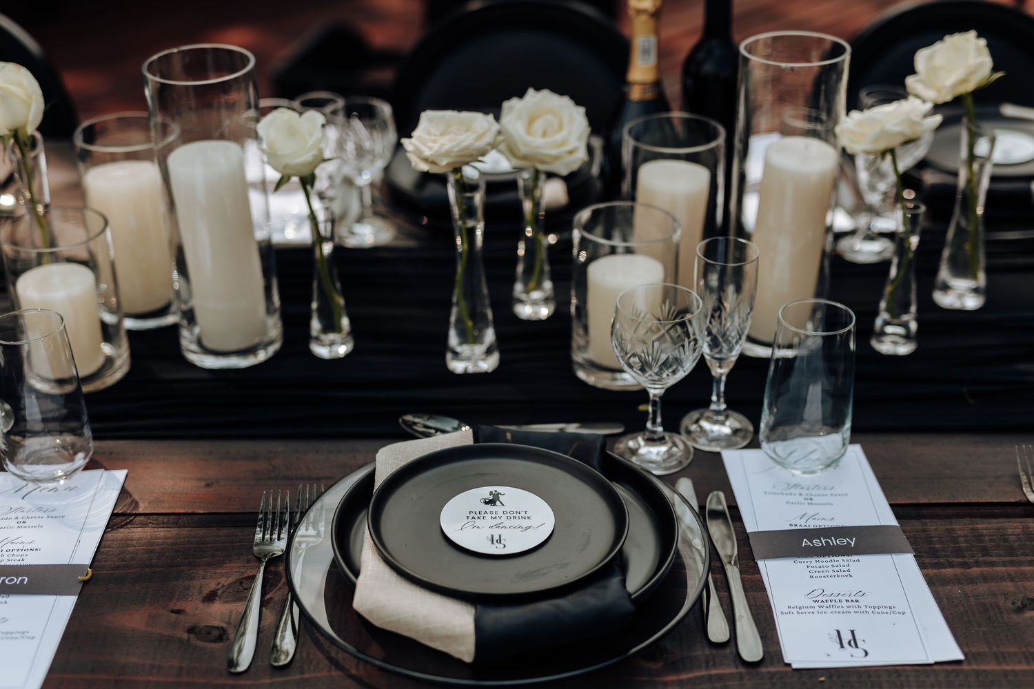 Elegant table settings with white roses, wine glasses, and vinyl records create a sophisticated dining atmosphere.